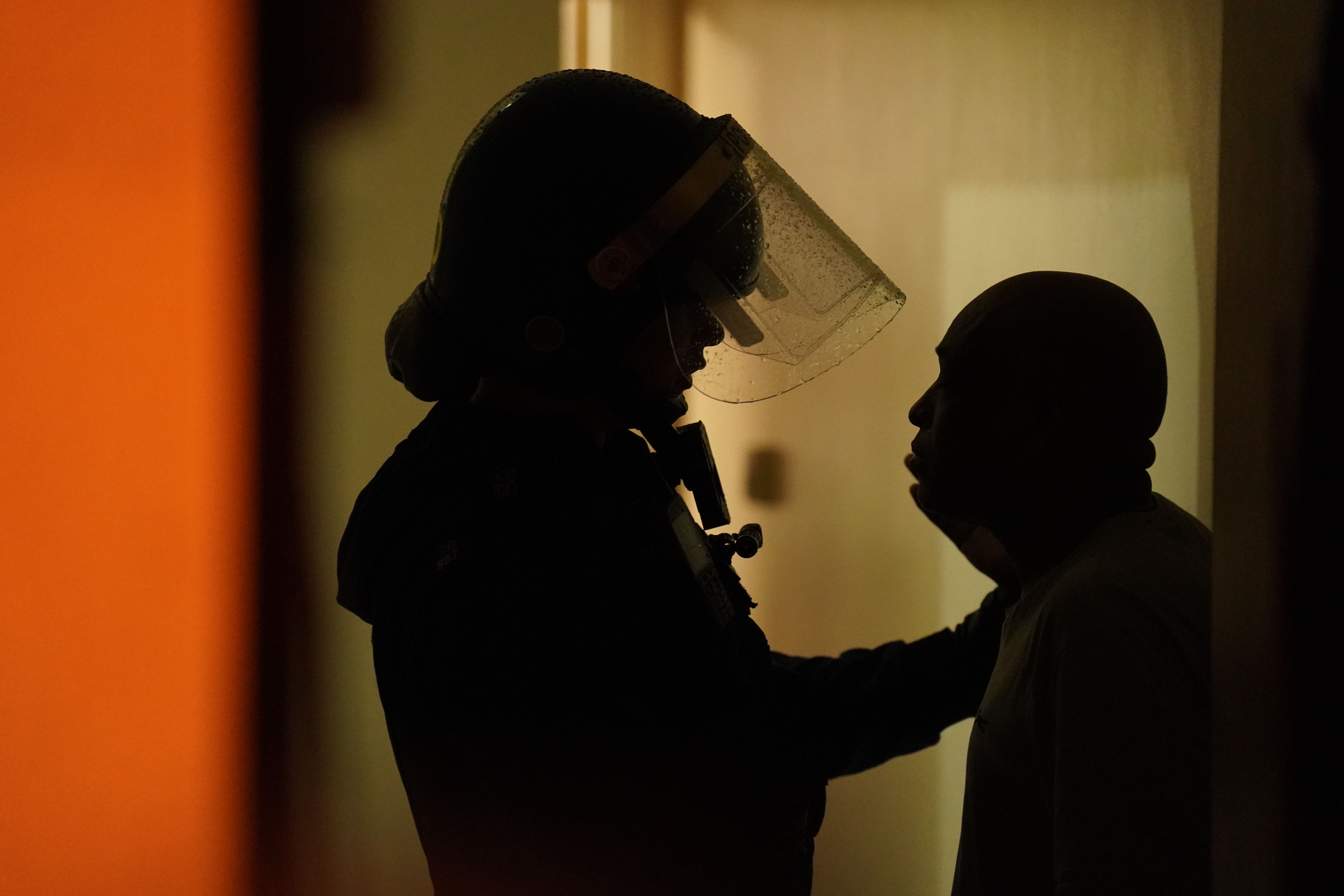 Officers from Metropolitan Police speak to a resident during the raid of a house in Islington, north London (PA)