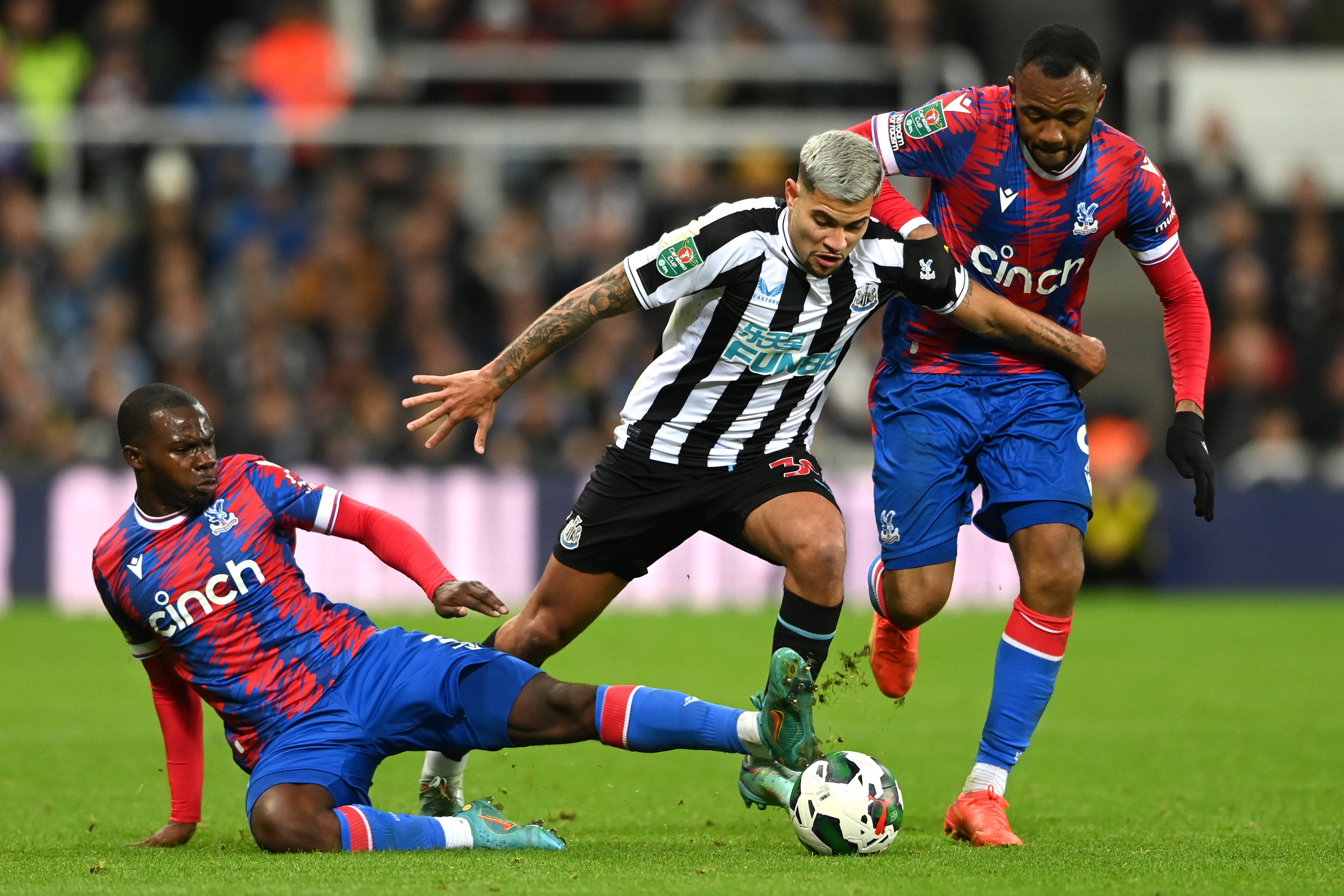 Bruno Guimaraes of Newcastle United is tackled by Tyrick Mitchell and Jordan Ayew