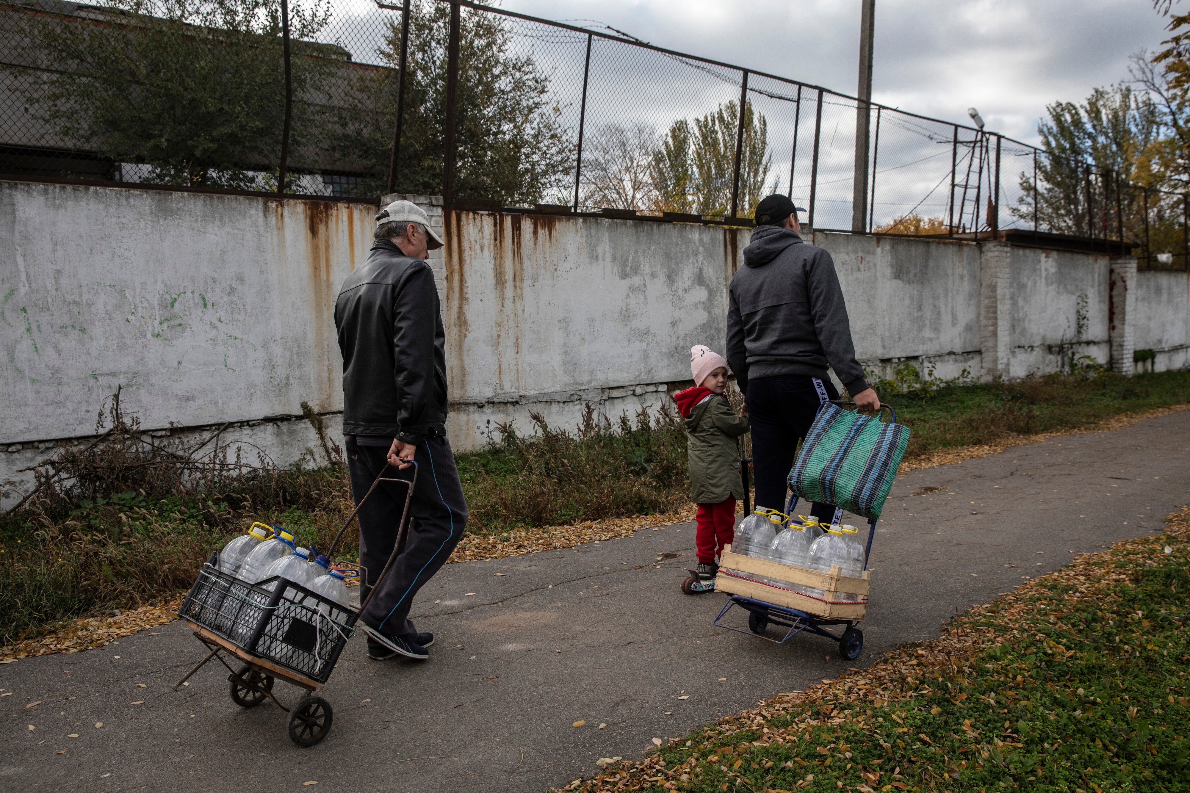 Residents use carts to take home plastic bottles of clean water