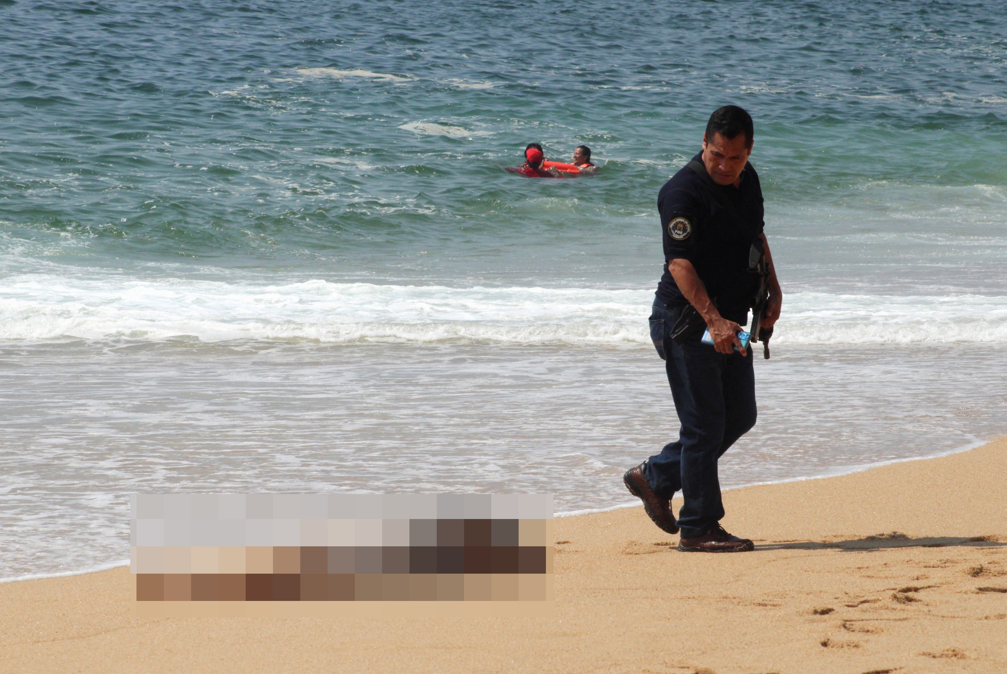 SENSITIVE MATERIAL. THIS IMAGE MAY OFFEND OR DISTURB A police officer walks near one of three bodies with signs of torture that have been washed ashore by the sea, according to local media, at Icacos beach, in