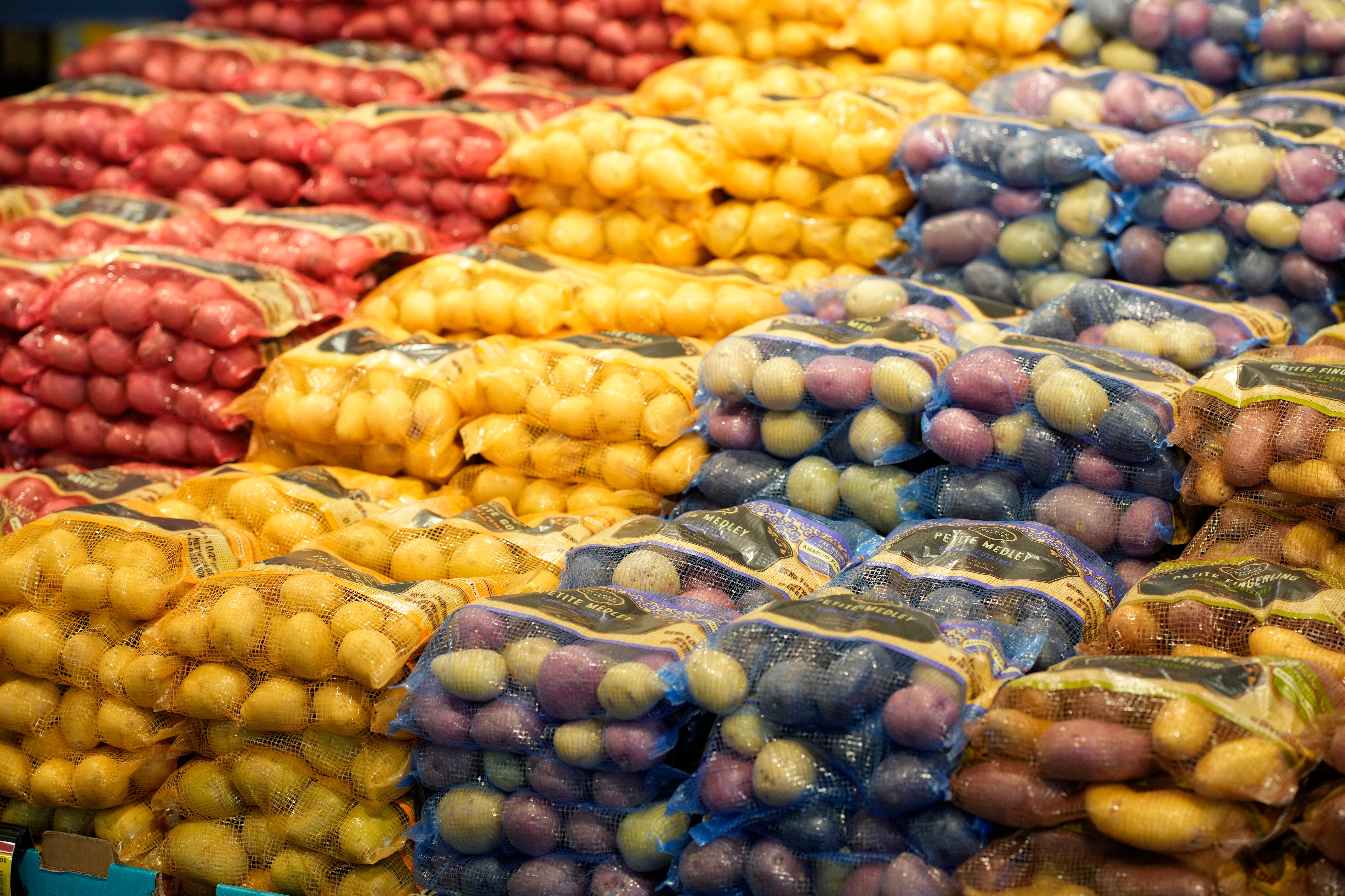 Bags of potatoes are displayed in a supermarket