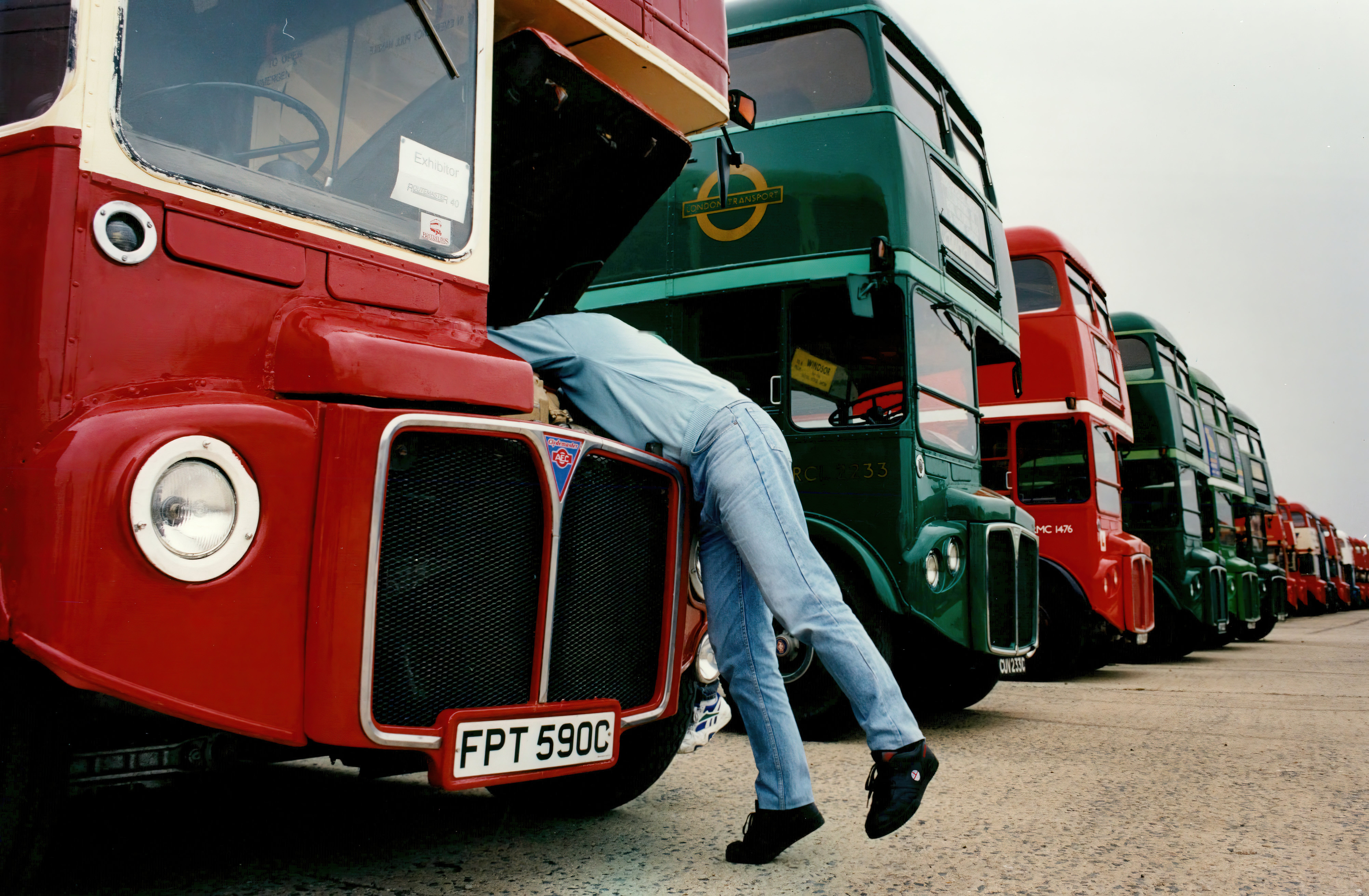 Man tinkers under bonnet of London bus in depot, date unknown.
