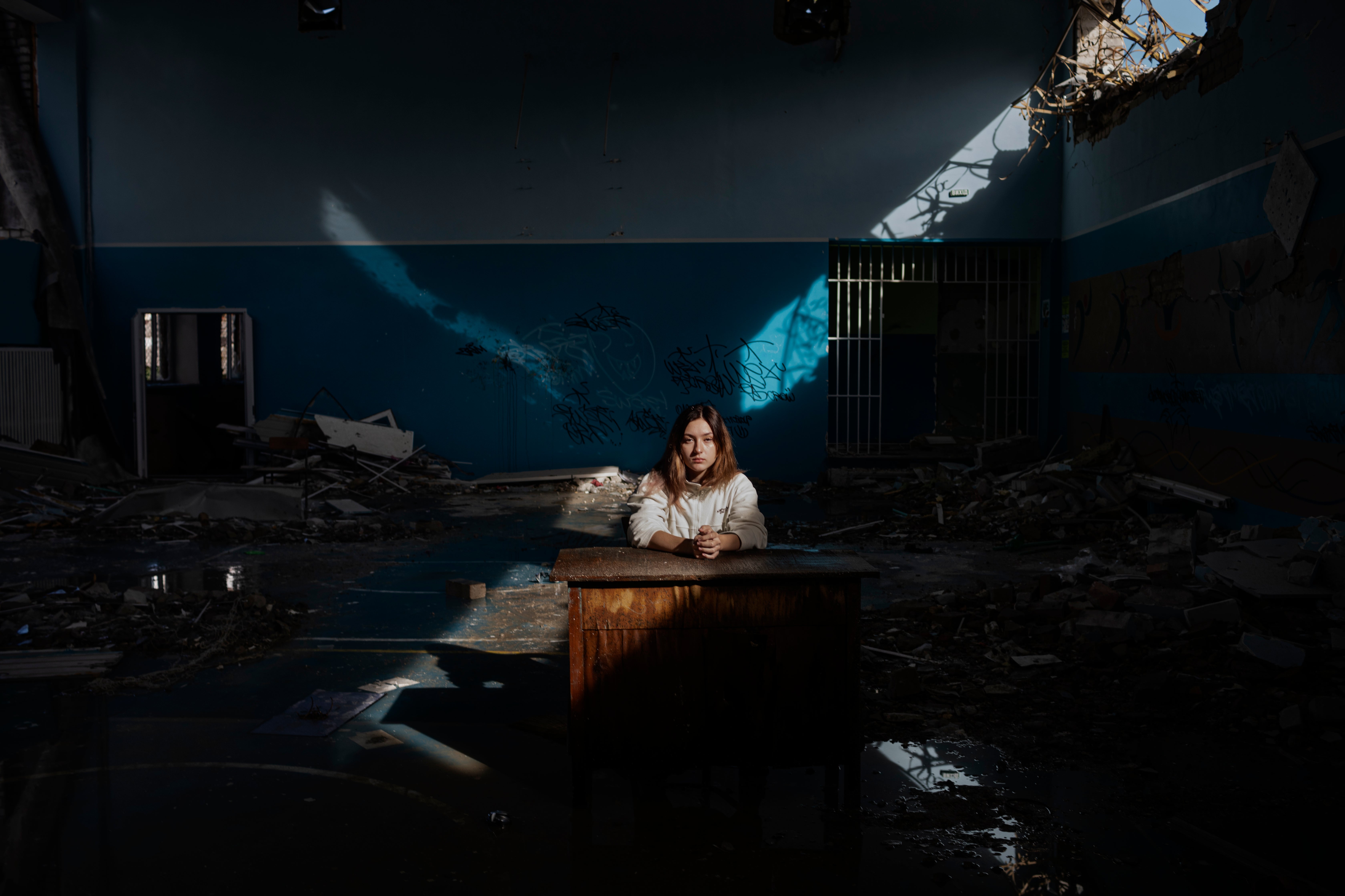 Daria Kechenovska sits inside her destroyed school in Zhytomyr