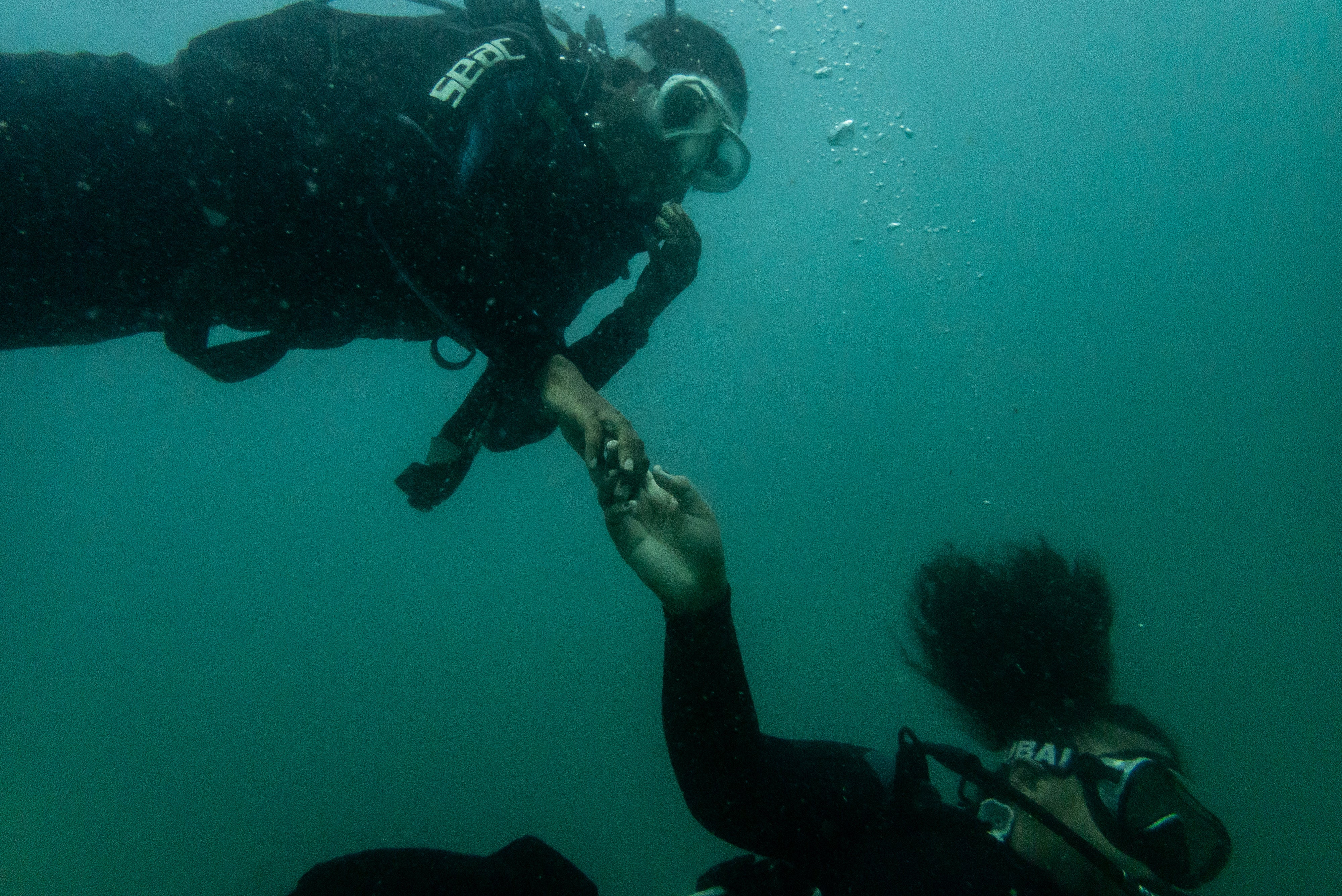 Gabrielle Miller takes Grace Grodje's hand to lead her down to the dive site