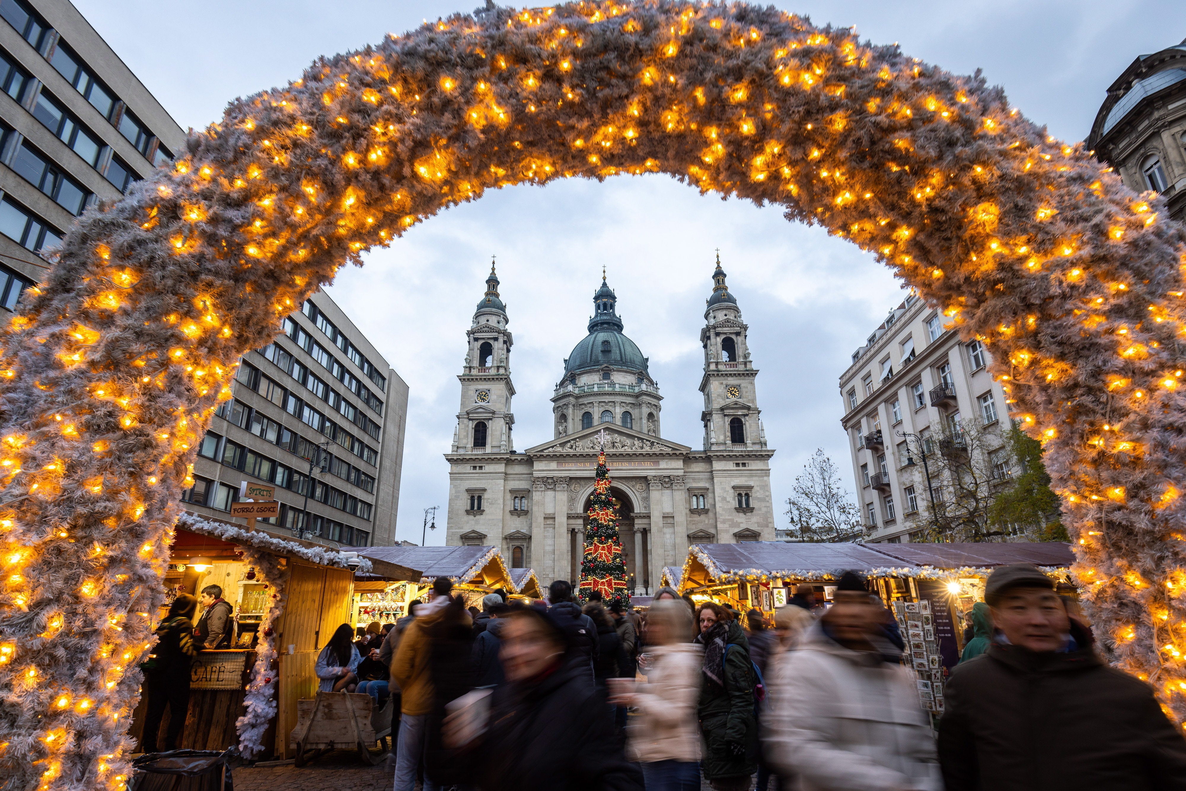 People stroll among stands of a Christmas market in the square in front of St. Stephen Basilica in downtown Budapest, Hungary