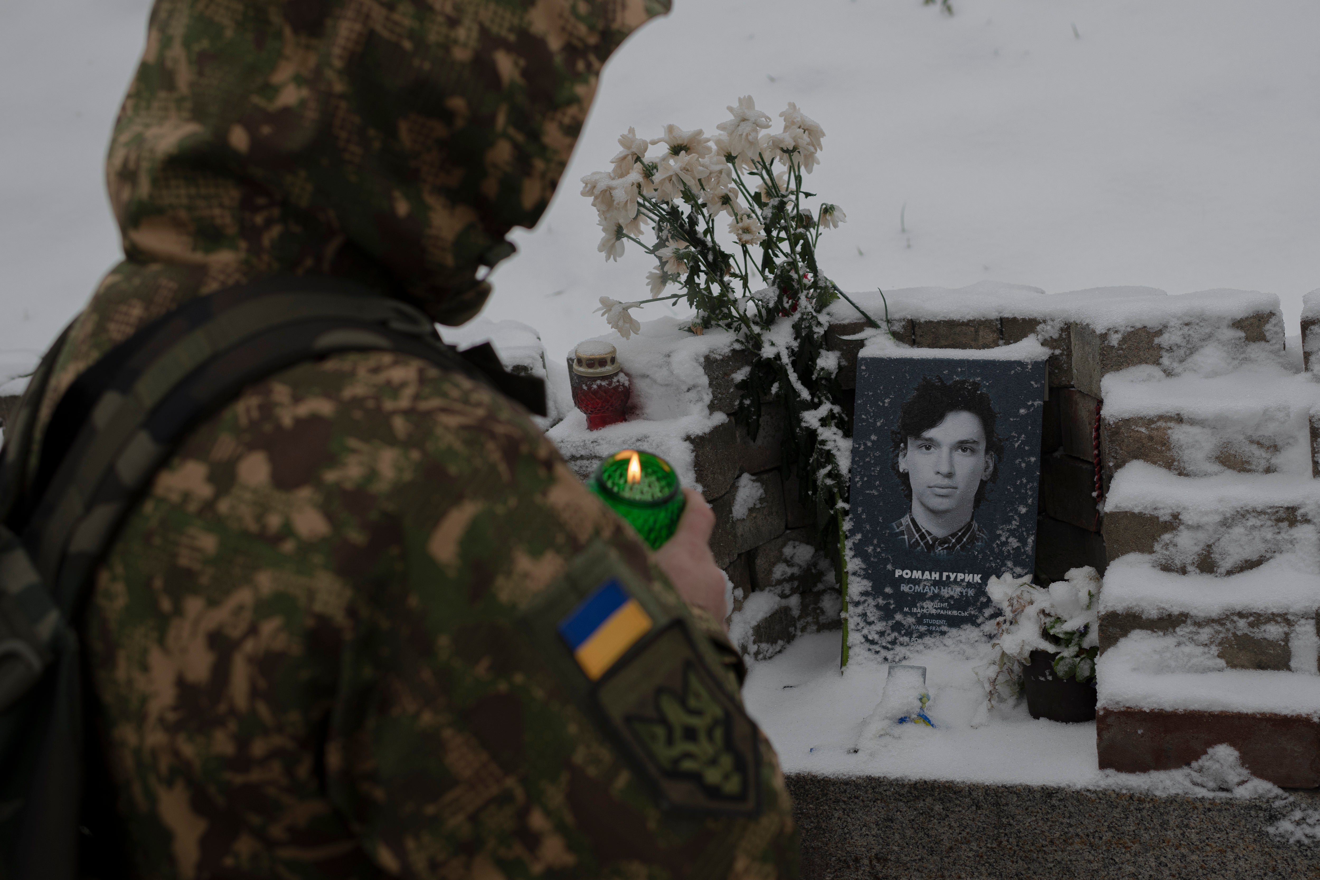 A Ukrainian serviceman lights a candle at a memorial in Kyiv