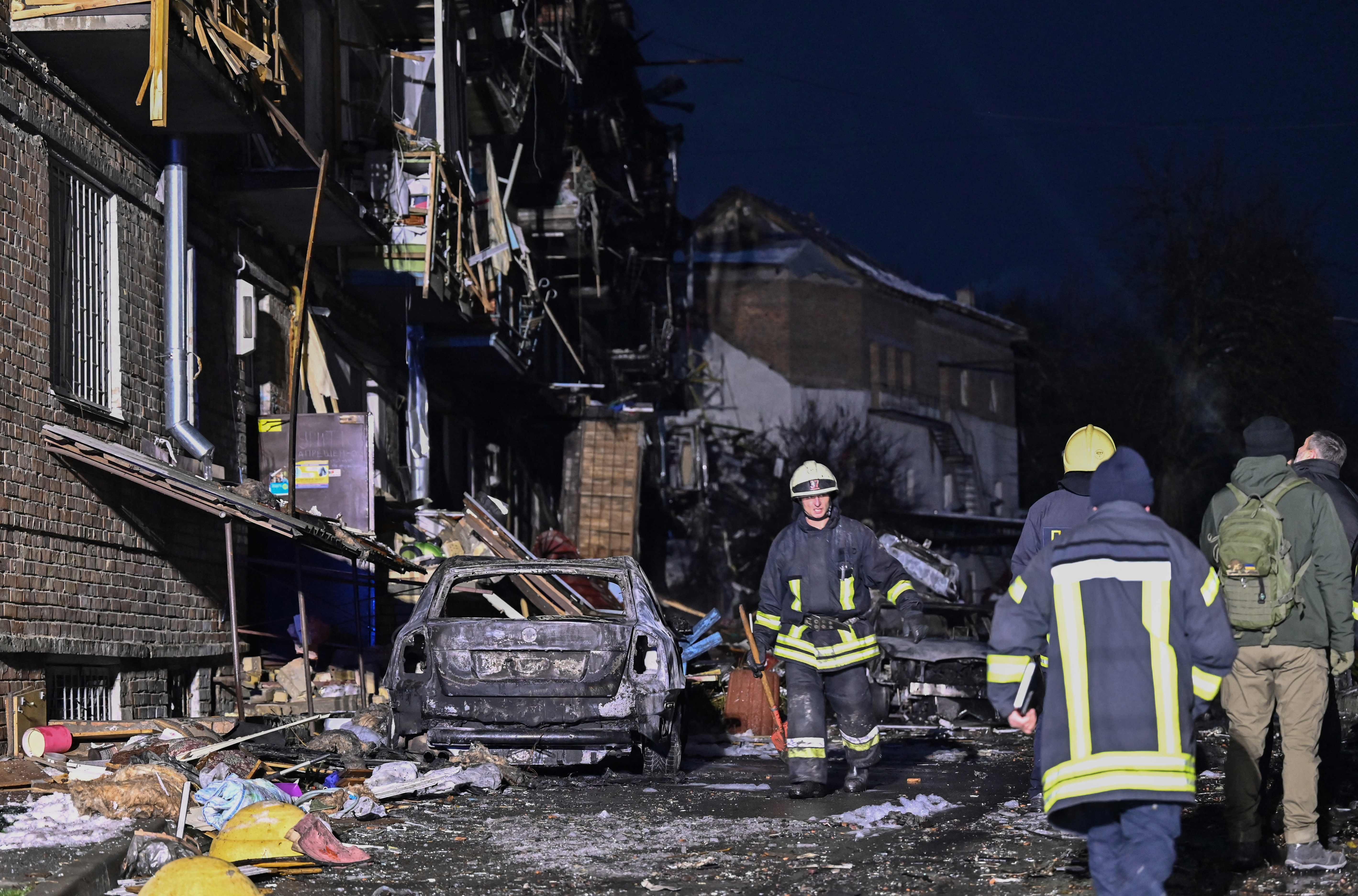 Rescuers work next to a damaged residential building after a Russian strike on the outskirts of Kyiv