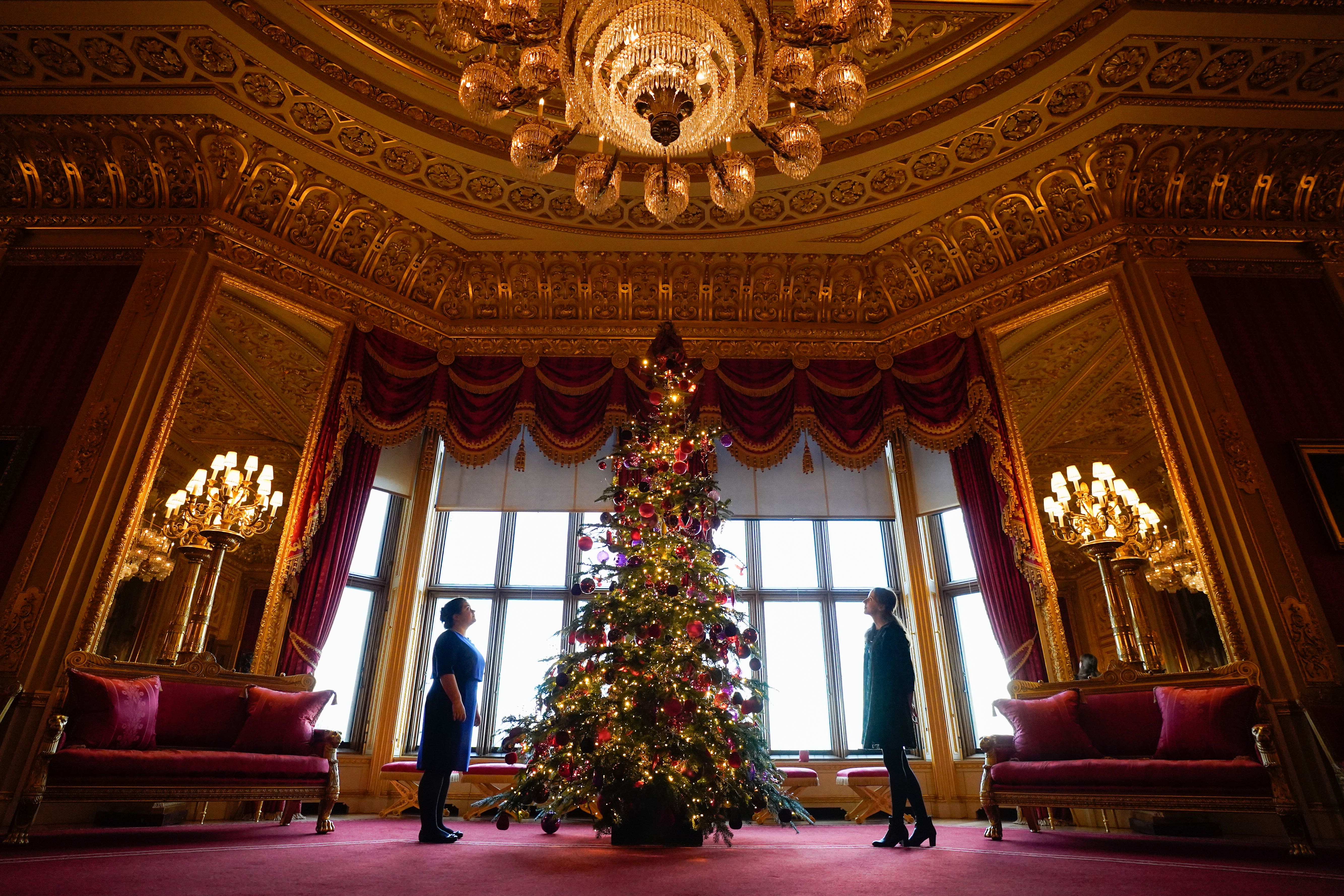 Members of the Royal Collection Trust look up at a Christmas tree on display in the Crimson Drawing Room (Andrew Matthews/PA)