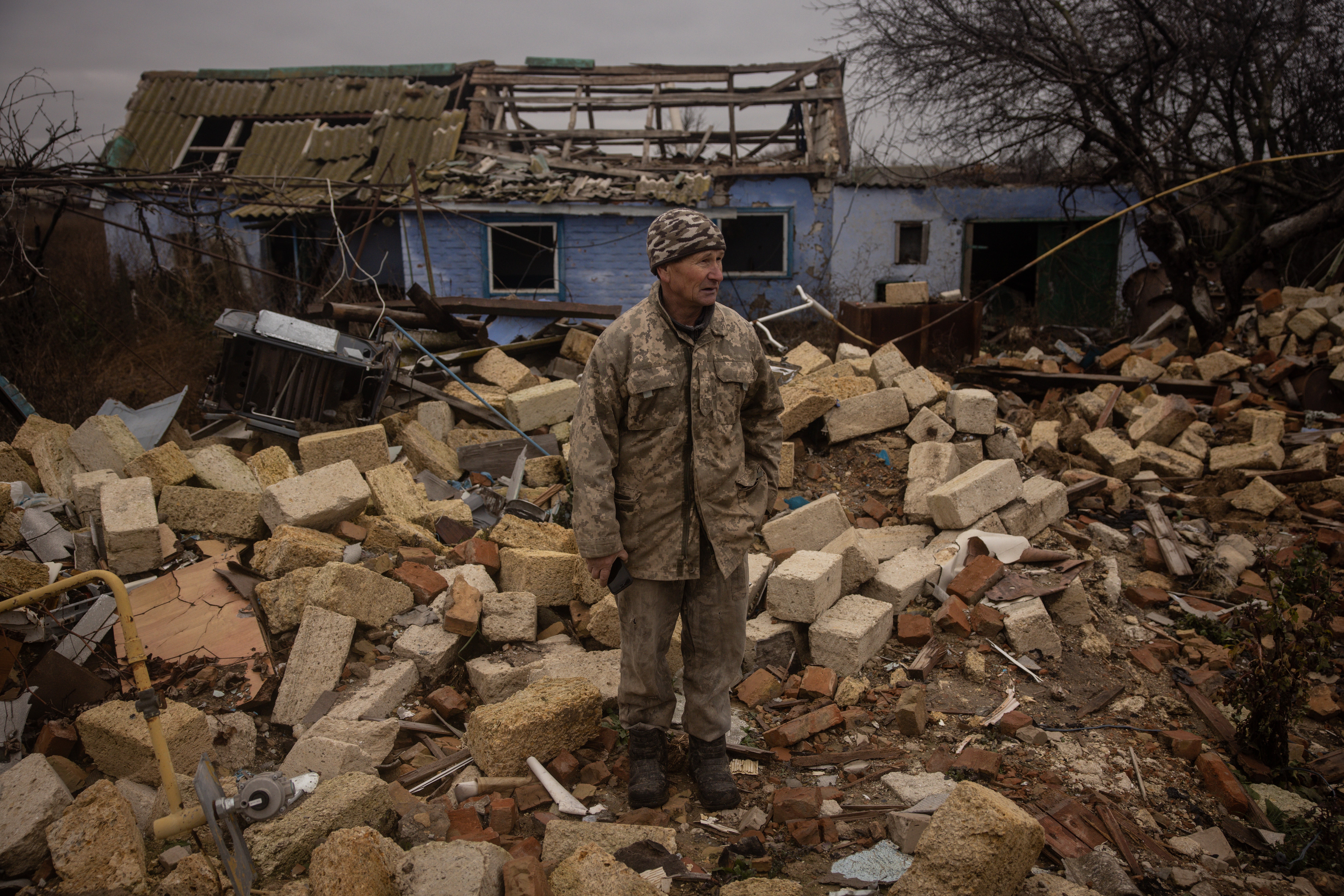 A Ukrainian stands in the rubble of a house on the outskirts of Kherson, where Russian forces allegedly killed seven men and one woman, hands bound, blindfolded and shot at close range