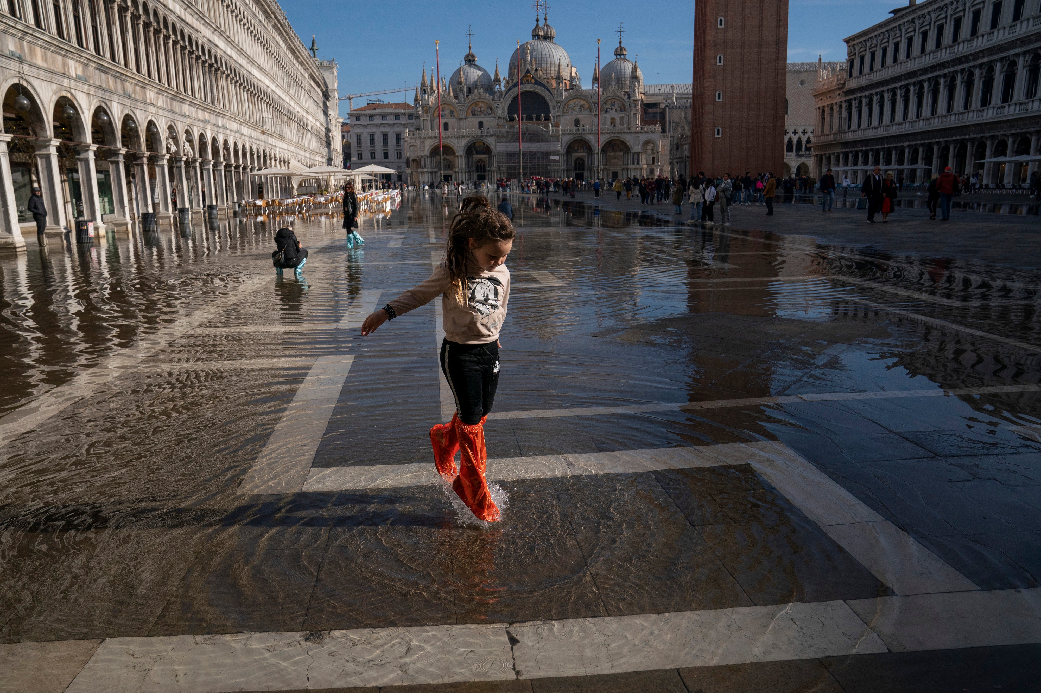 A 7-year-old plays in the normal high-tide waters of Piazza San Marco