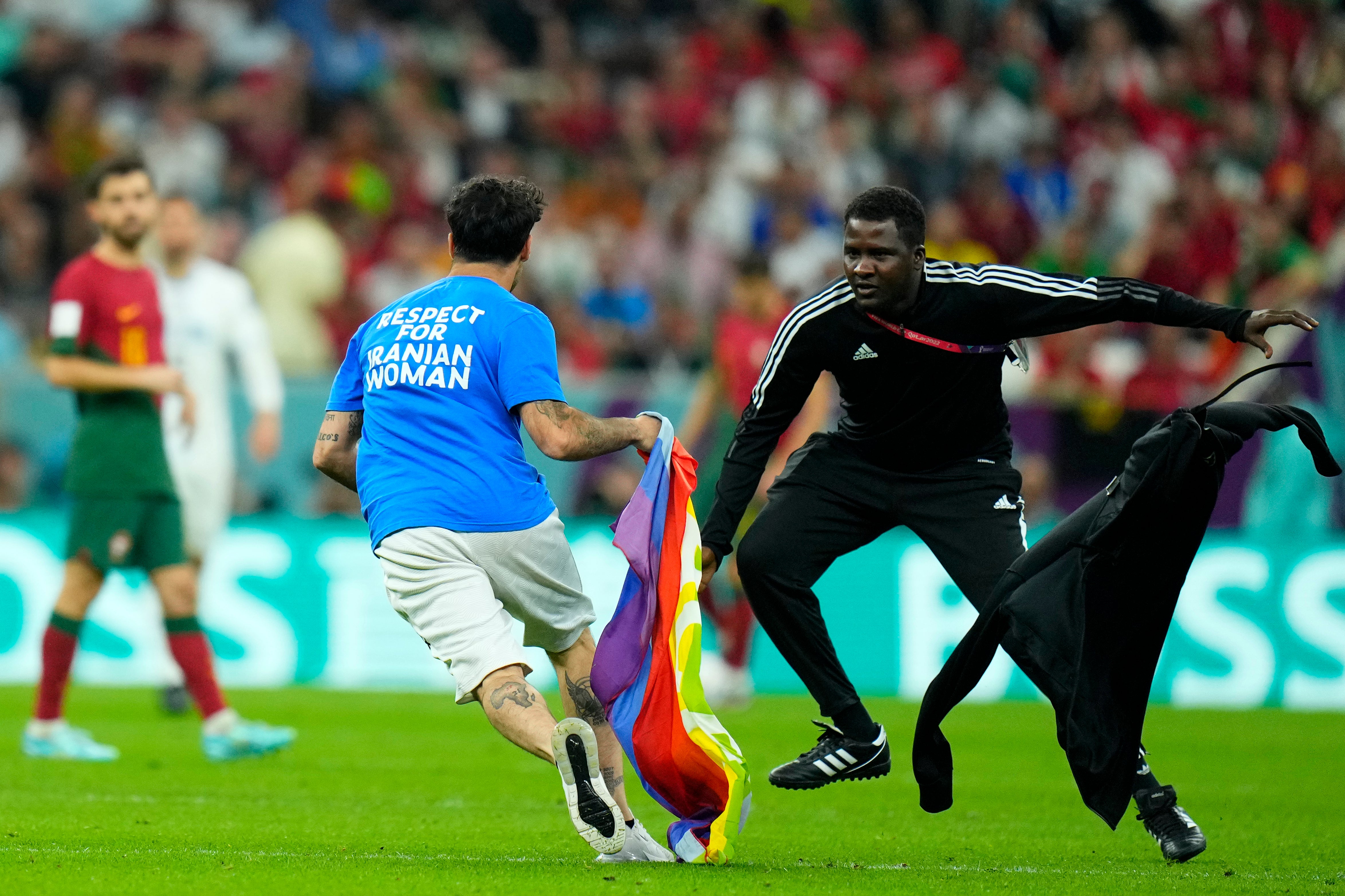 A pitch invader runs across the field with a rainbow flag during the match between Portugal and Uruguay