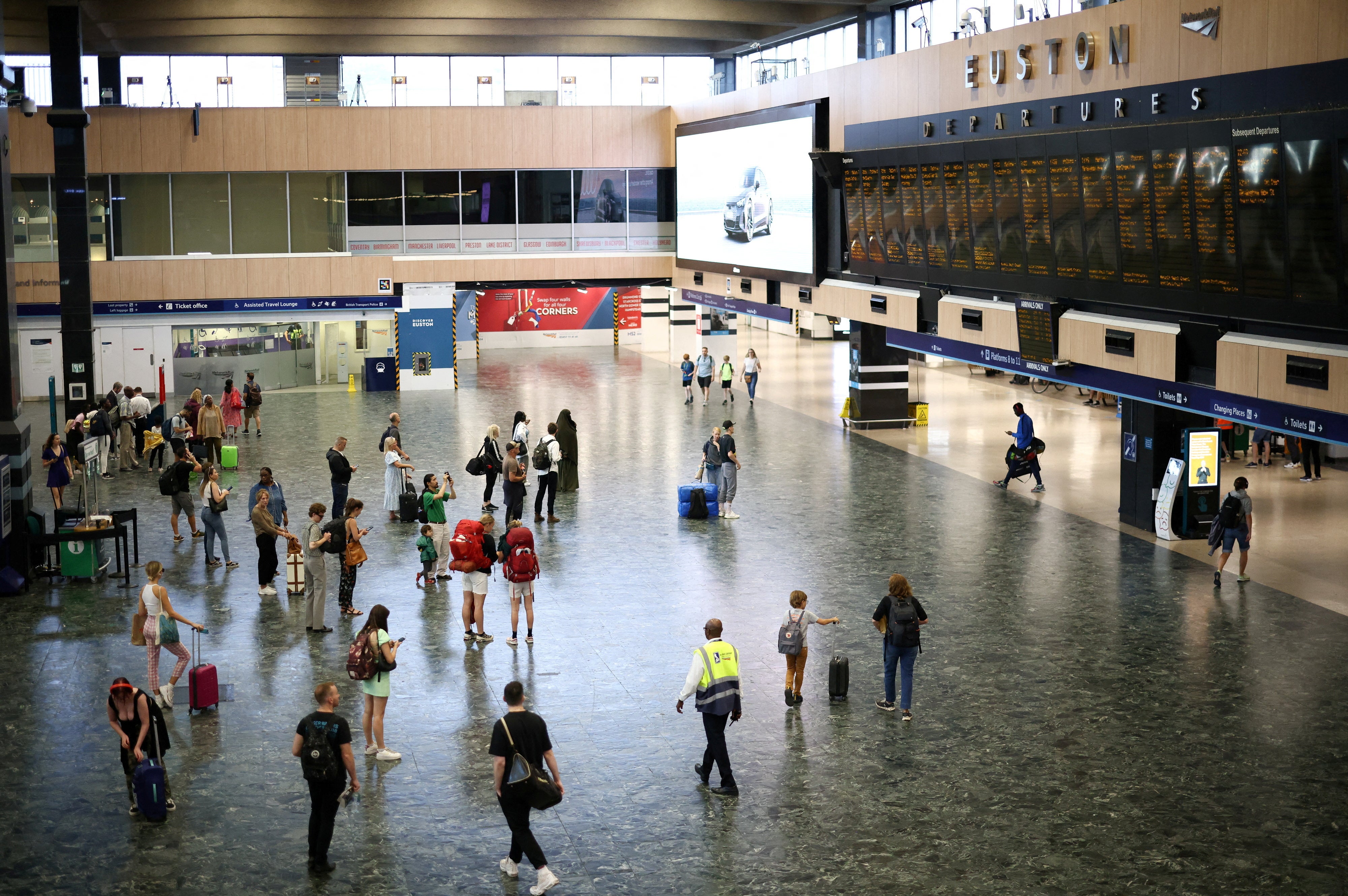 People look at departure information screens at Euston railway station during the August rail strikes