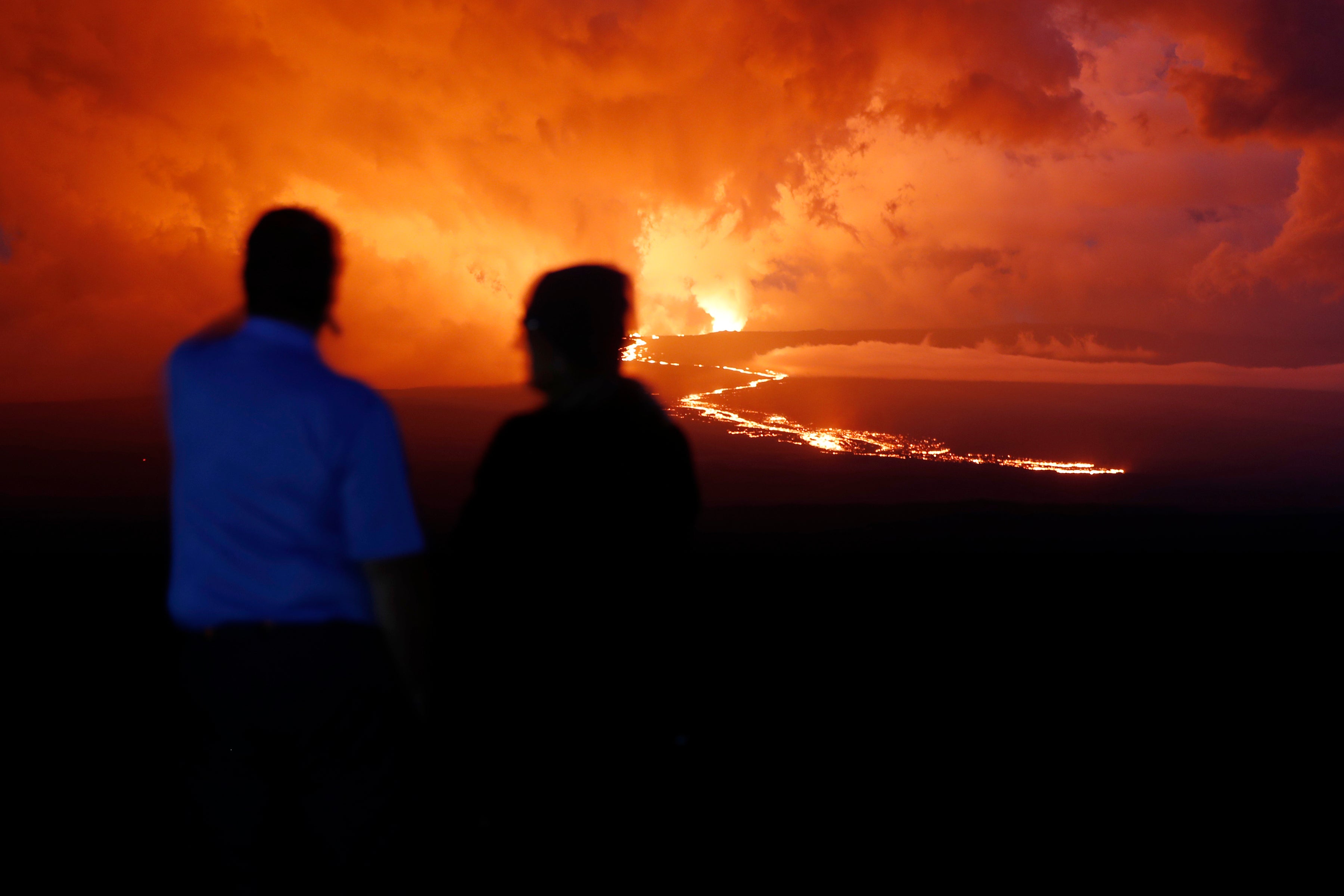 Spectators watch the lava flow down the mountain from the Mauna Loa eruption, Tuesday, Nov. 29, 2022, near Hilo, Hawaii