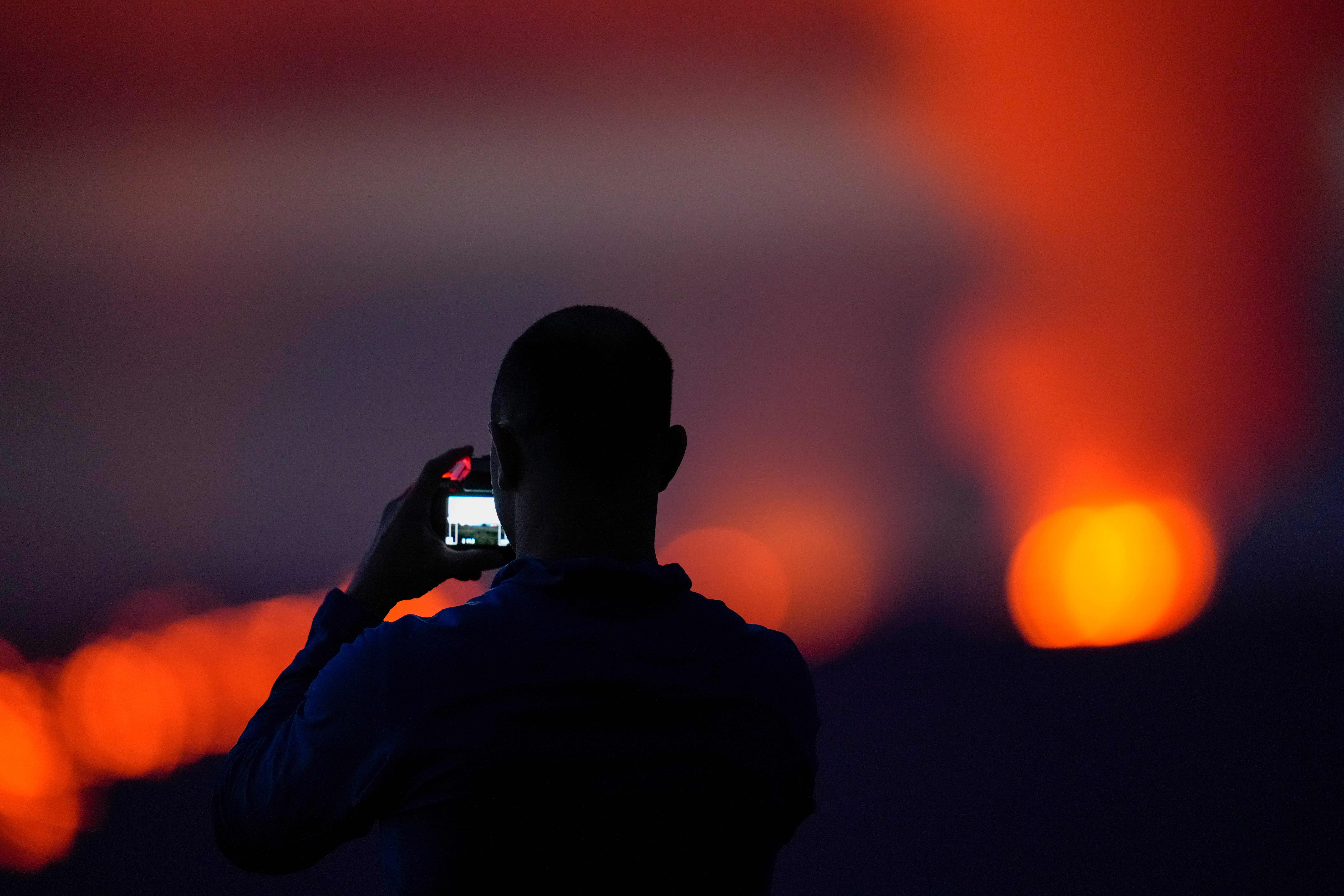 Brian Lichtenstein, of San Diego, takes a photo in front of lava erupting from Hawaii's Mauna Loa volcano Wednesday, Nov. 30, 2022, near Hilo, Hawaii