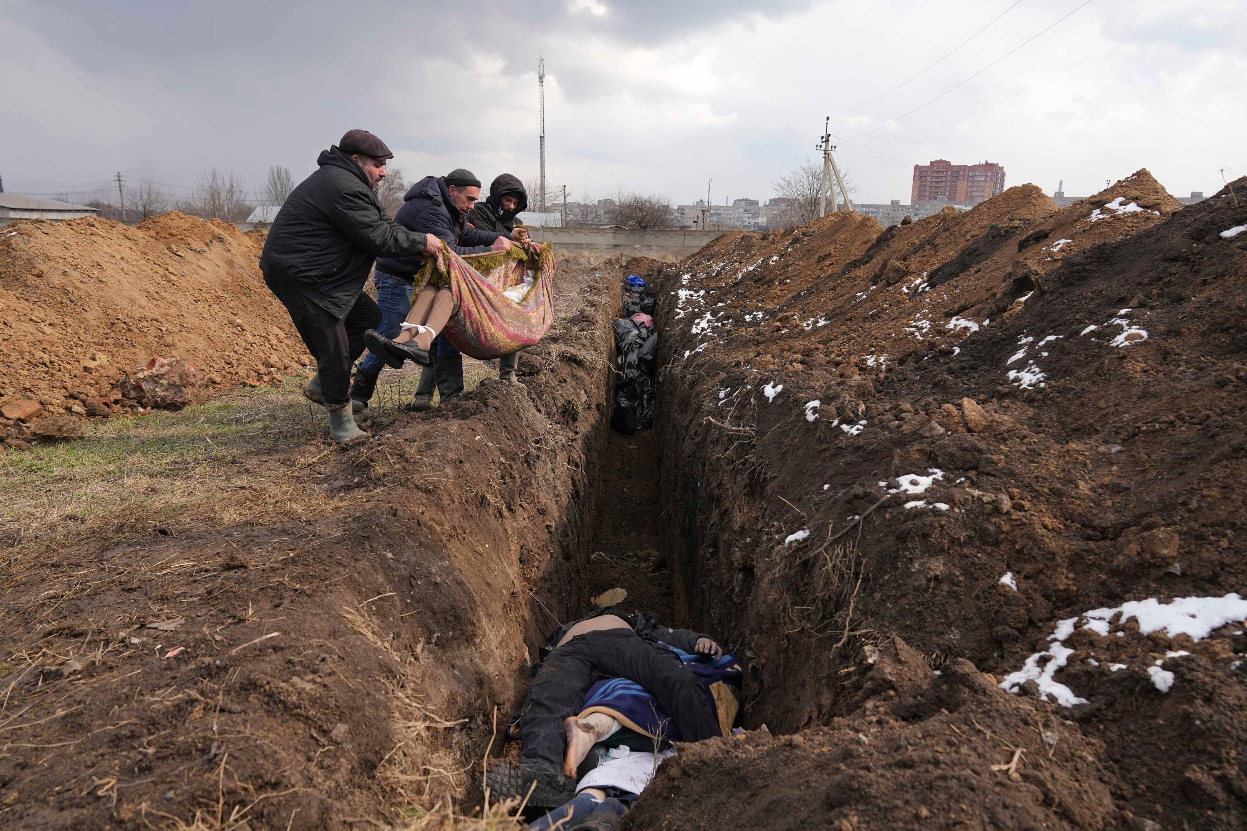 Bodies are lowered into a mass grave on the outskirts of Mariupol