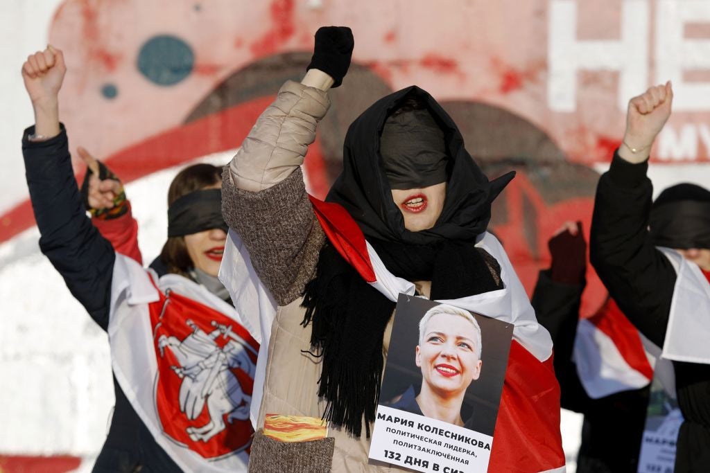 A blindfolded feminist activist holds a photograph of Kolesnikova during protests against police violence in Minsk