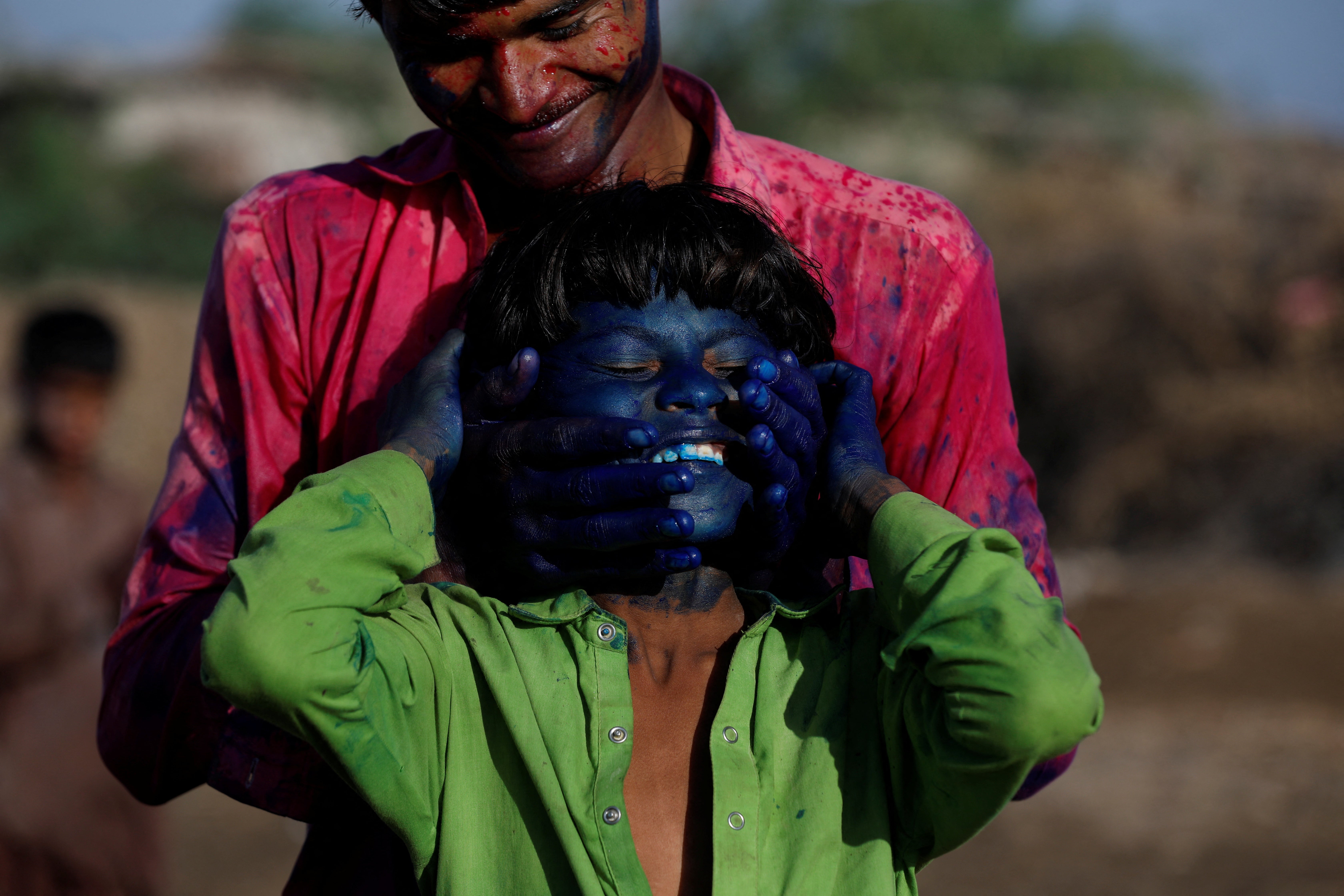 Red chilli pepper farmers smear colour on their face as they celebrate Holi