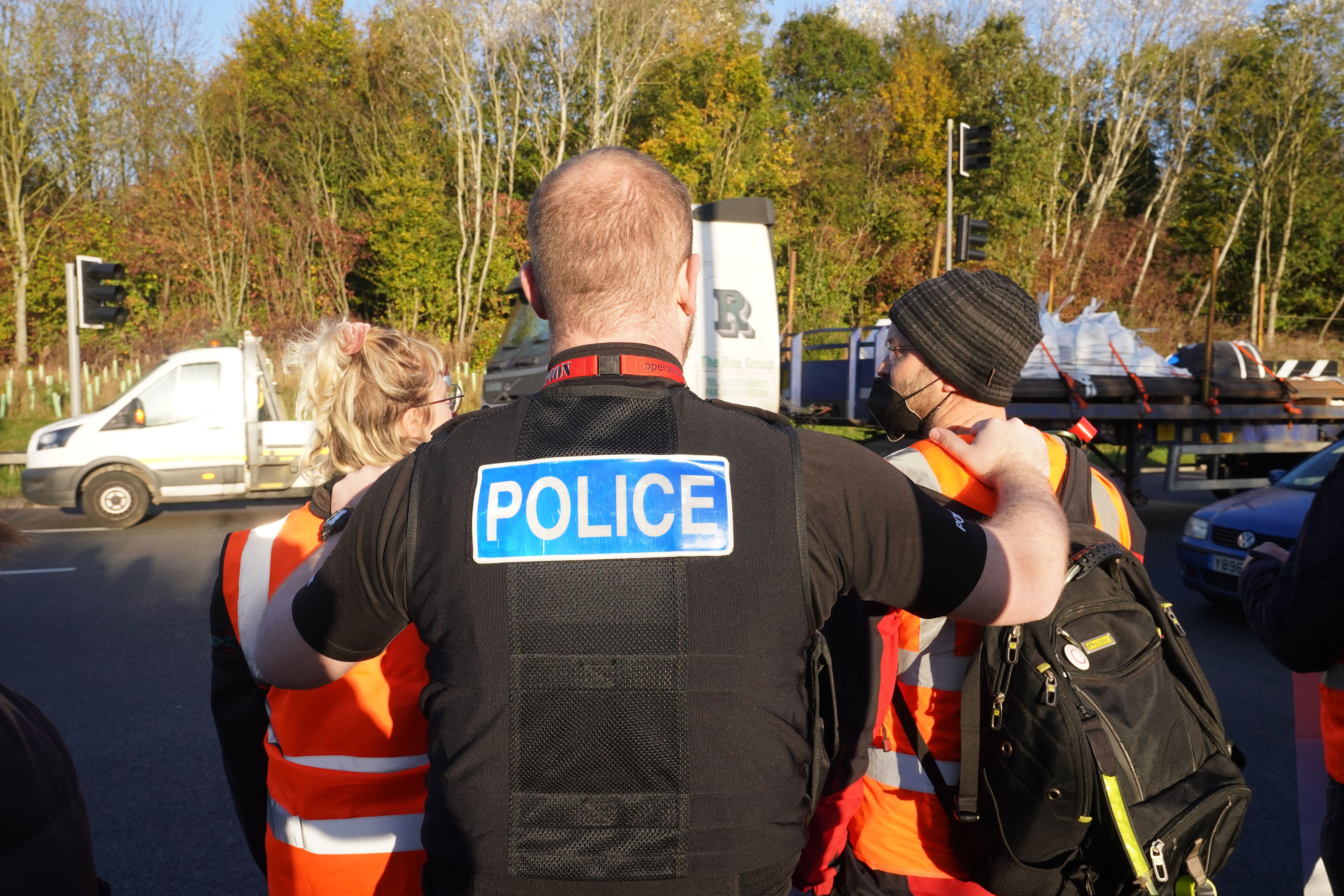 A police officer speaks to protesters at an Insulate Britain roadblock (PA)