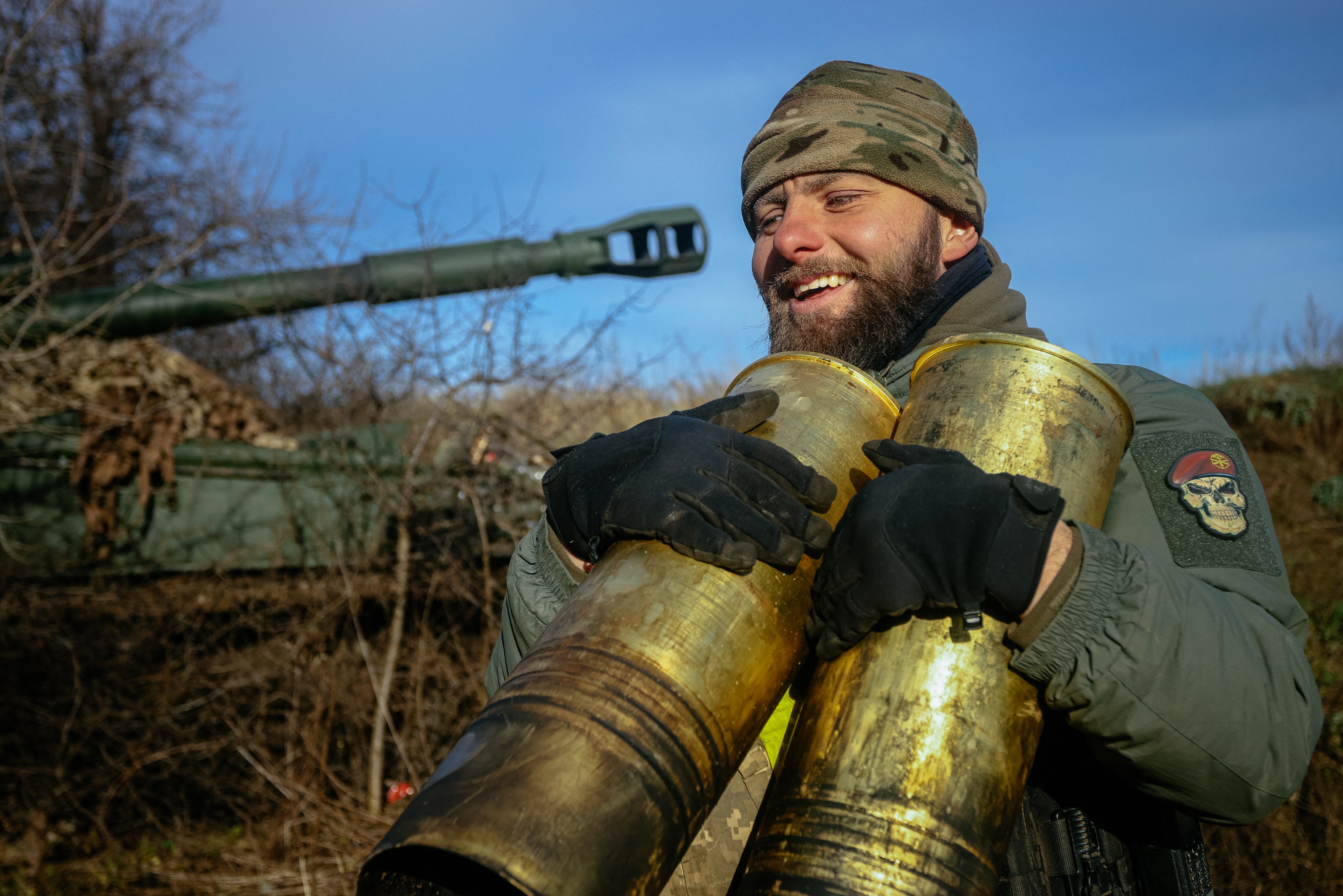 A Ukrainian artilleryman carries empty cartridges from a 152 mm 2S3 Akatsiya (self-propelled howitzer)