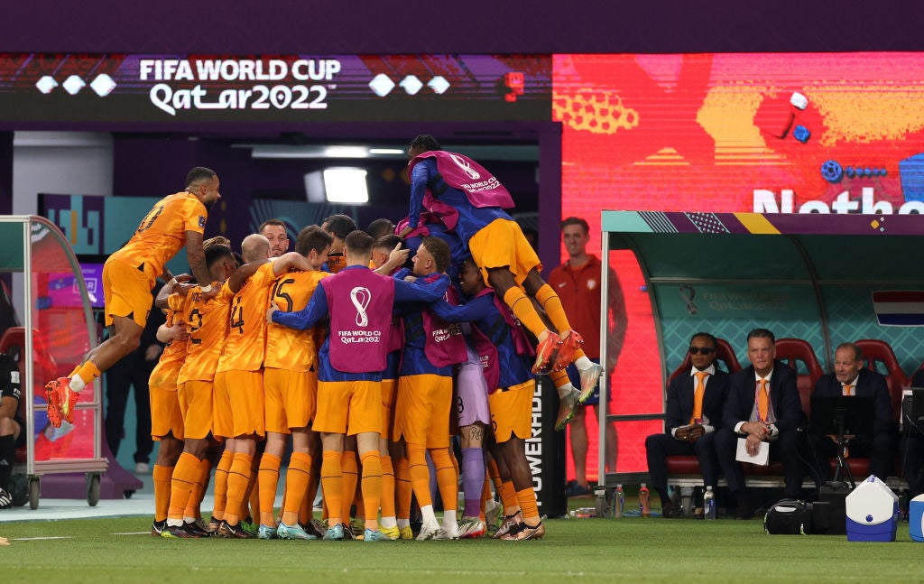 Daley Blind celebrates with teammates after scoring his side's second goal while his father, assistant coach Danny (seated far right) looks on