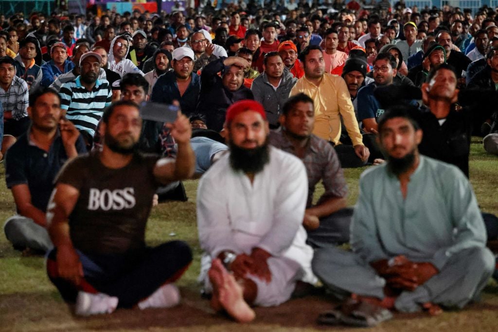 Migrant workers watch the World Cup match between Spain and Germany on the outskirts of Doha