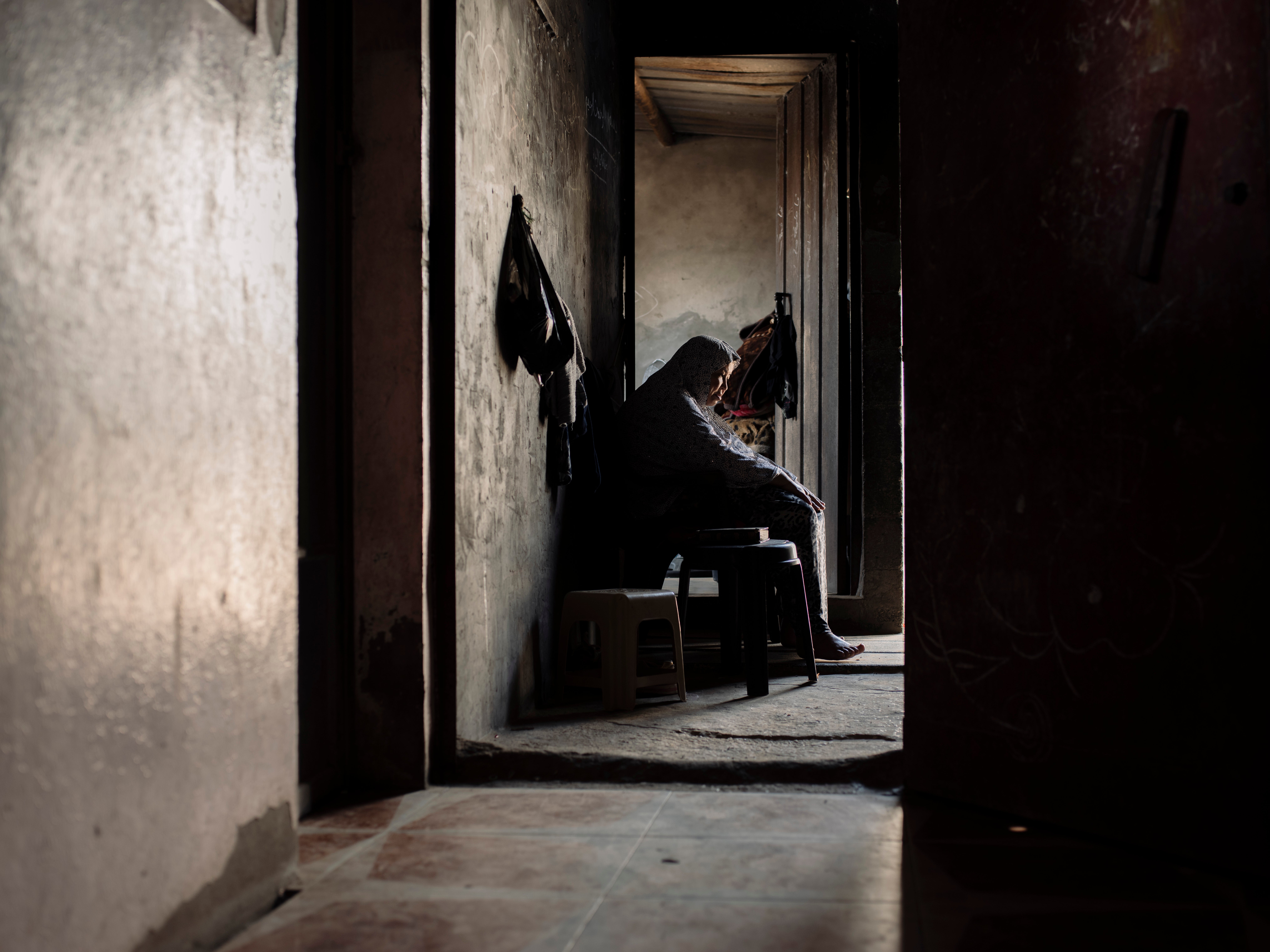 An elderly lady sits near the entrance to her family home waiting for a breeze to cut through the relentless coastal humidity