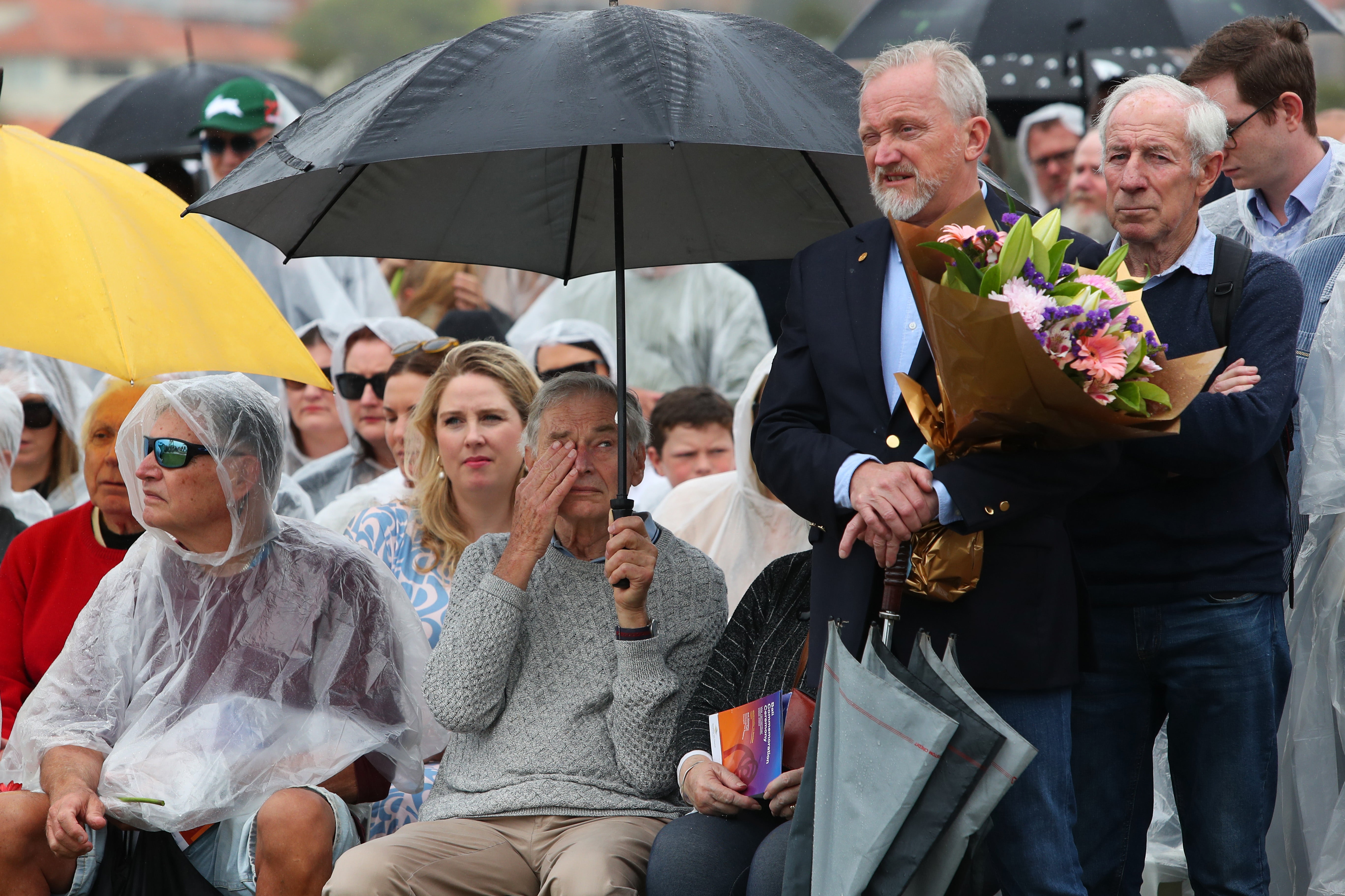 Family and community members stand for a moment of silence during the Bali Bombing Commemoration Ceremony at Dolphins Point, Coogee Beach