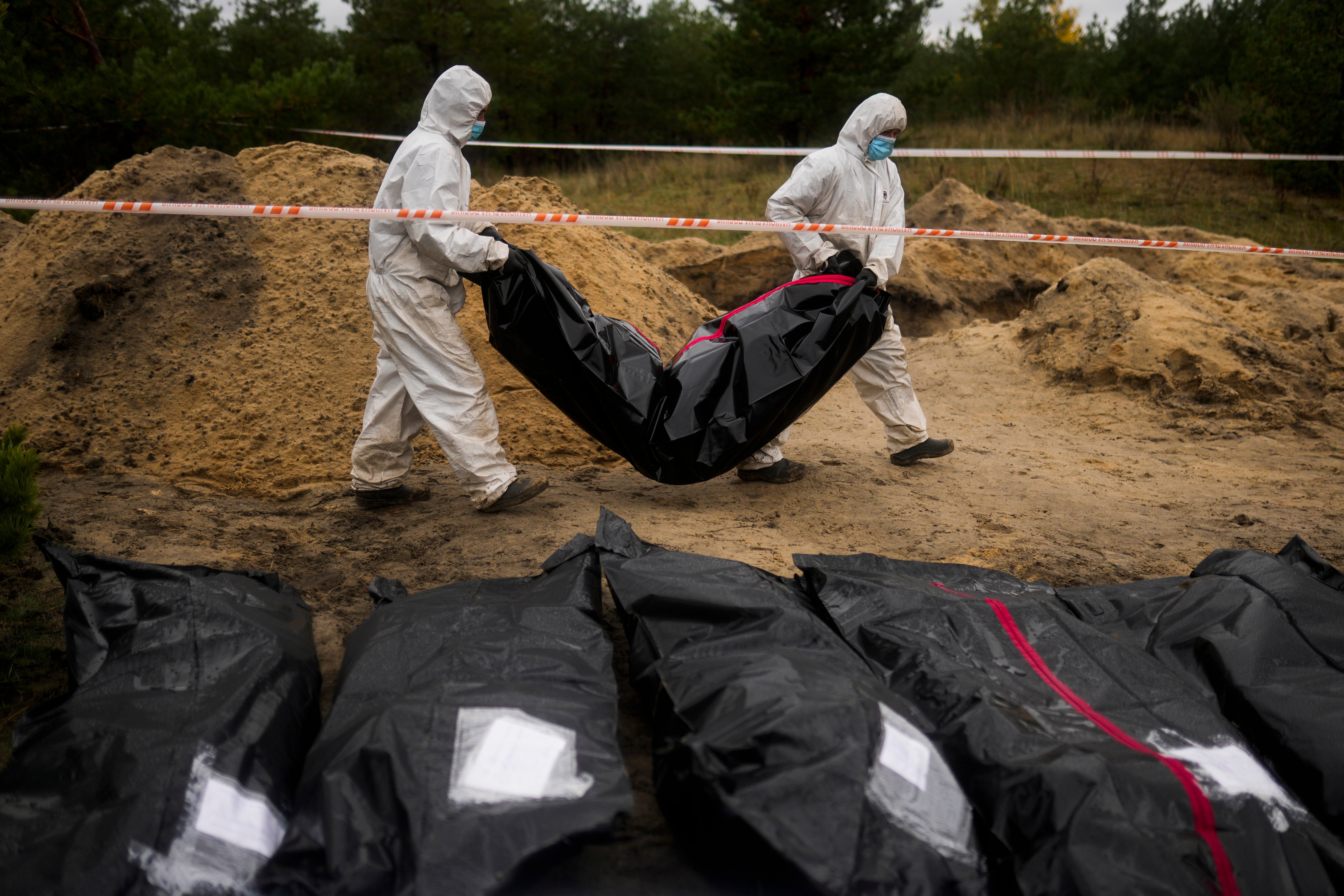 Members of a forensic team work on a mass grave in Lyman, Ukraine