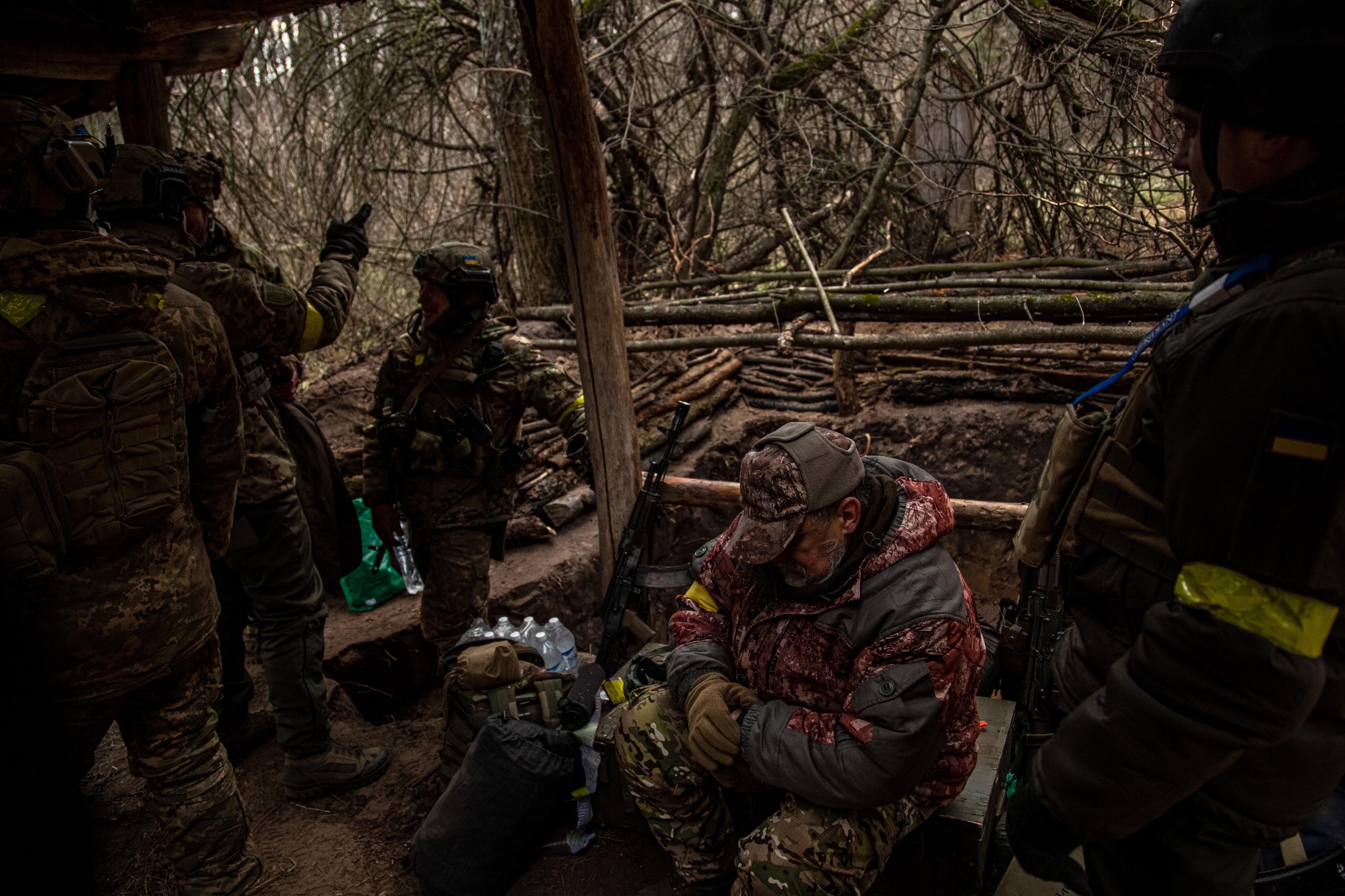 Soldiers from the Fifth Brigade of Ukraine's National Guard emerge from a trench after a pause in Russian shelling