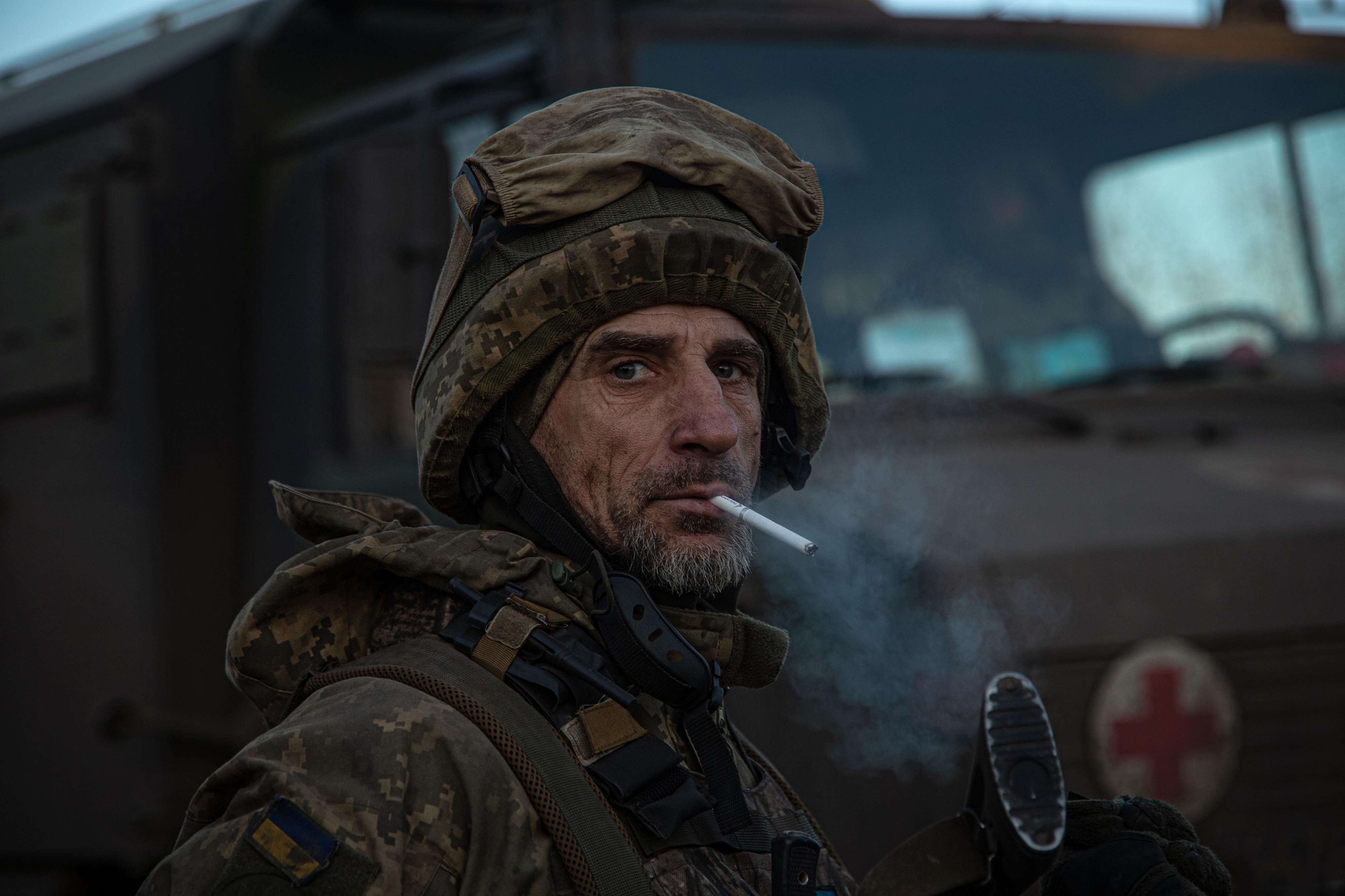 A Ukrainian soldier smokes near a car that was waiting for two wounded soldiers close to the eastern front