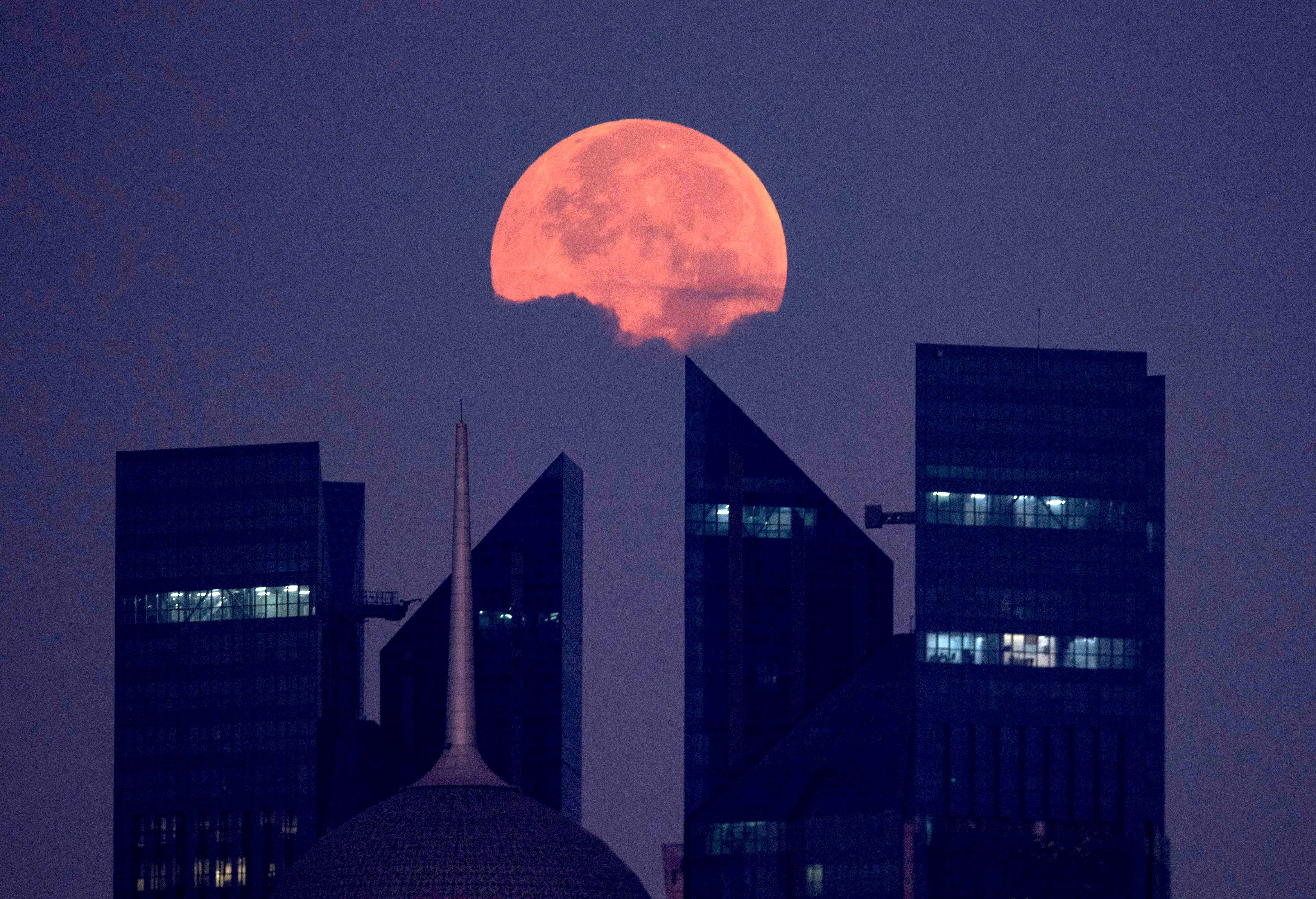 The full moon sets behind the skyline of Doha in the early morning