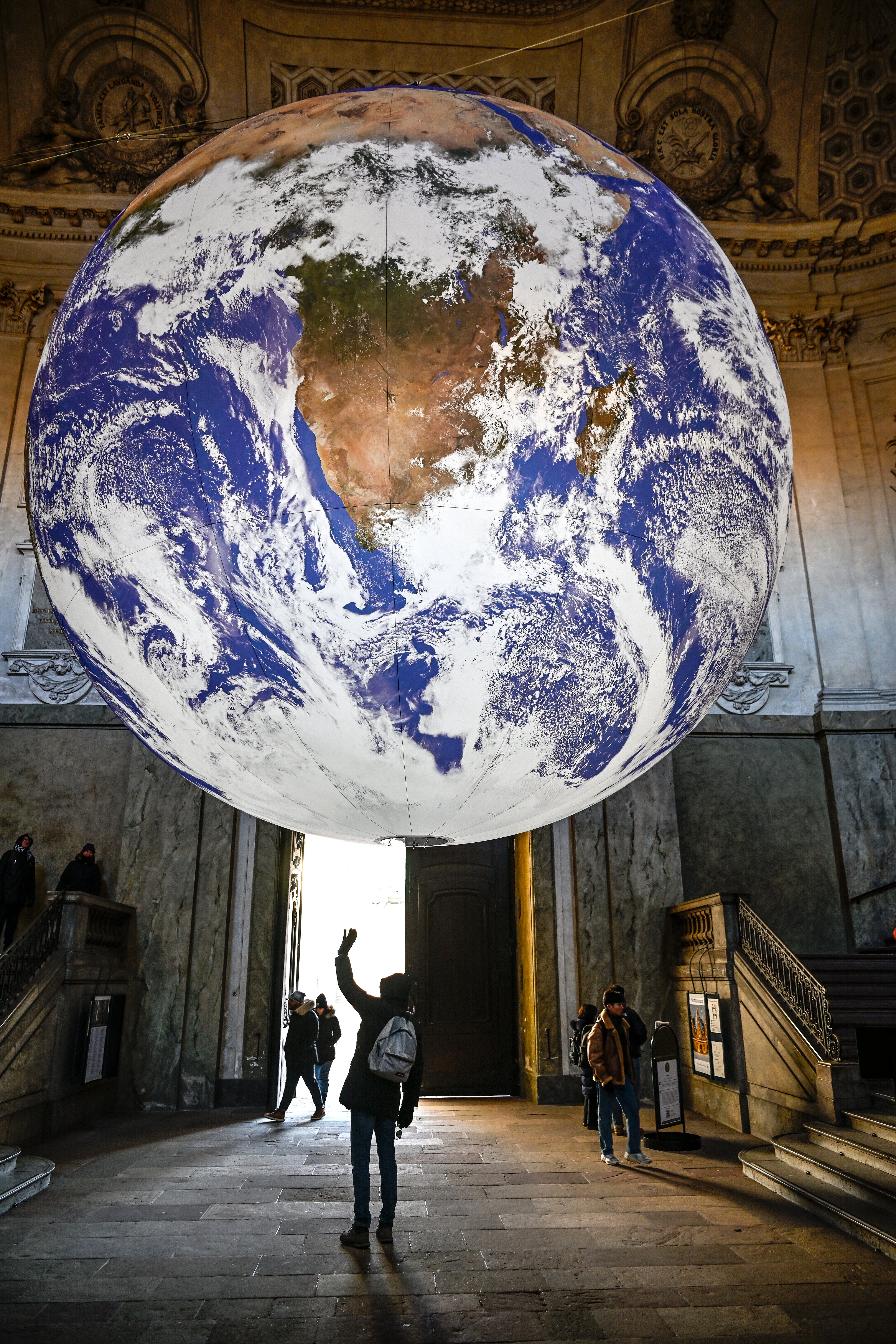 Visitors look at the artwork ‘Gaia’ by artist Luke Jerram, hanging in the Royal Palace’s south vault, in Stockholm, Sweden