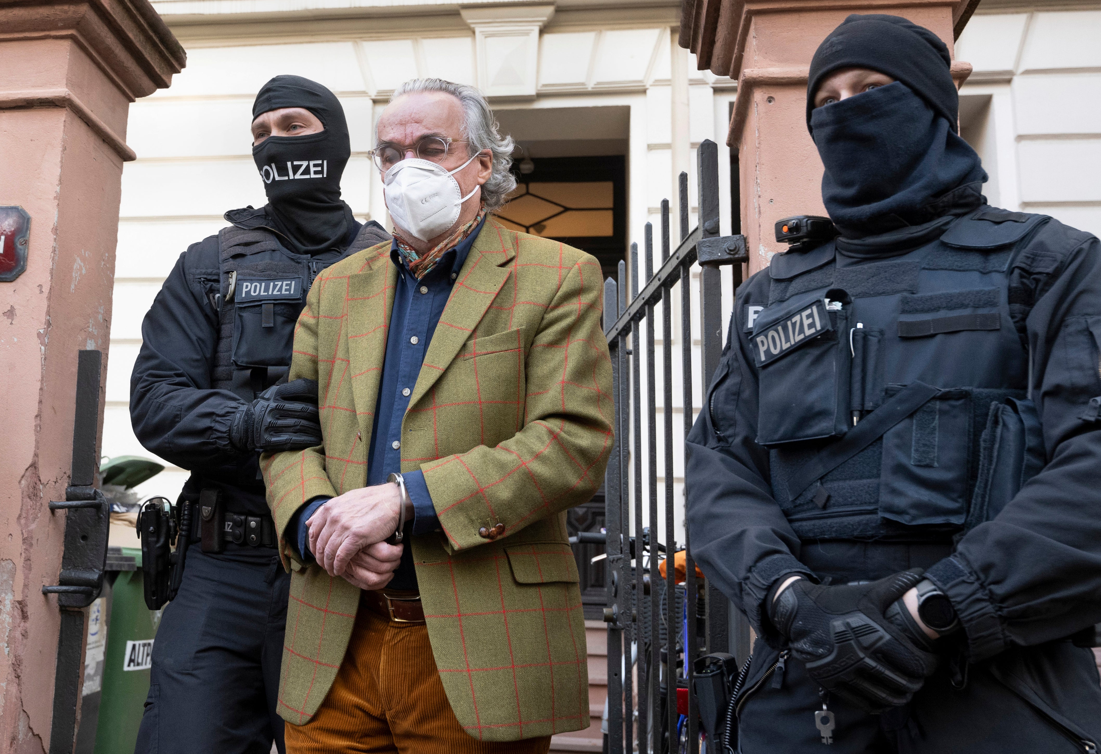 Masked police officers lead Heinrich XIII Prince Reuss, centre, to a police vehicle during a raid against so-called ‘Reich citizens’ in Frankfurt