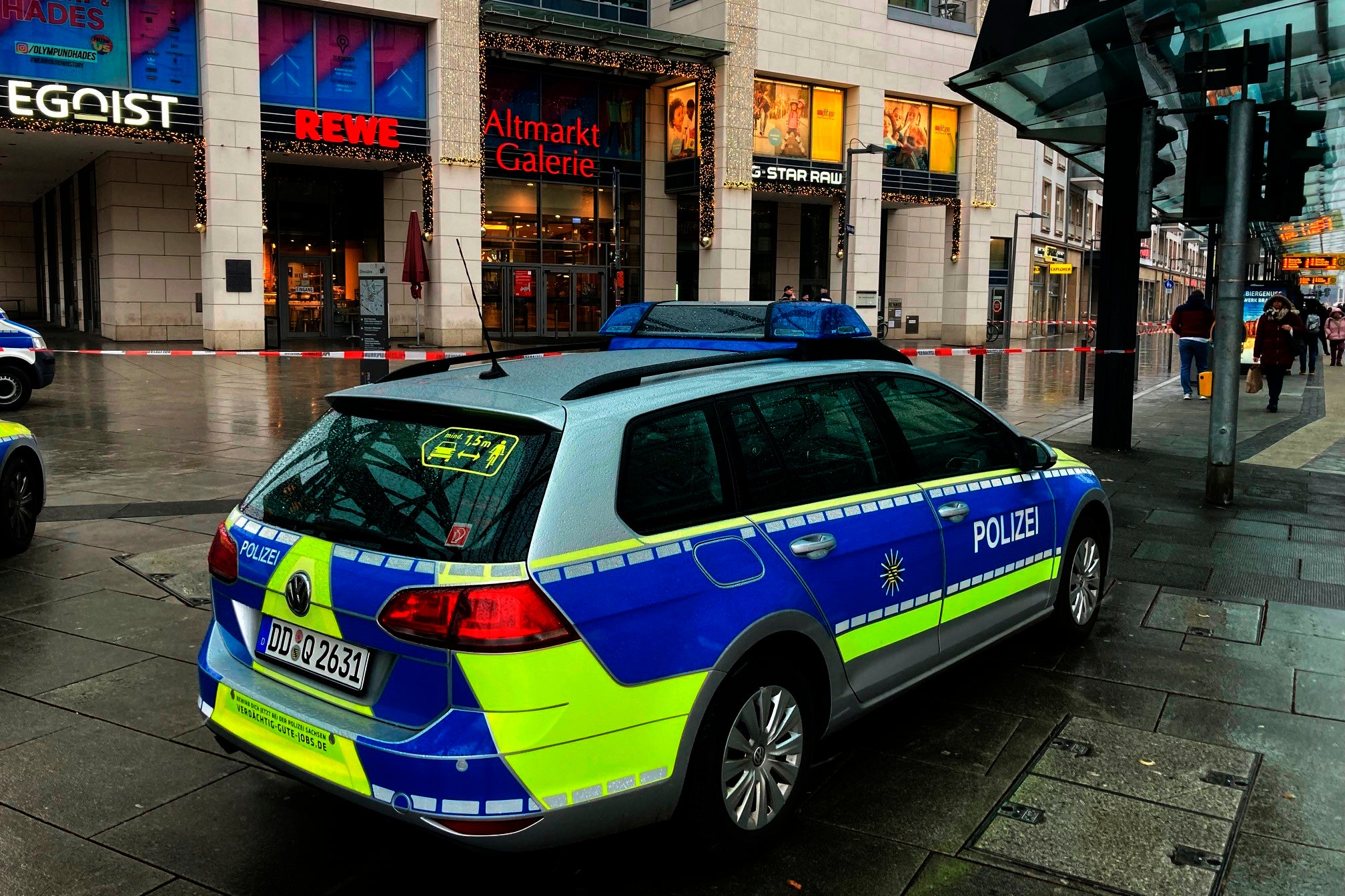 Police vehicles are parked around a cordoned off area at the Altmarktgalerie during a hostage situation in Dresden, Germany