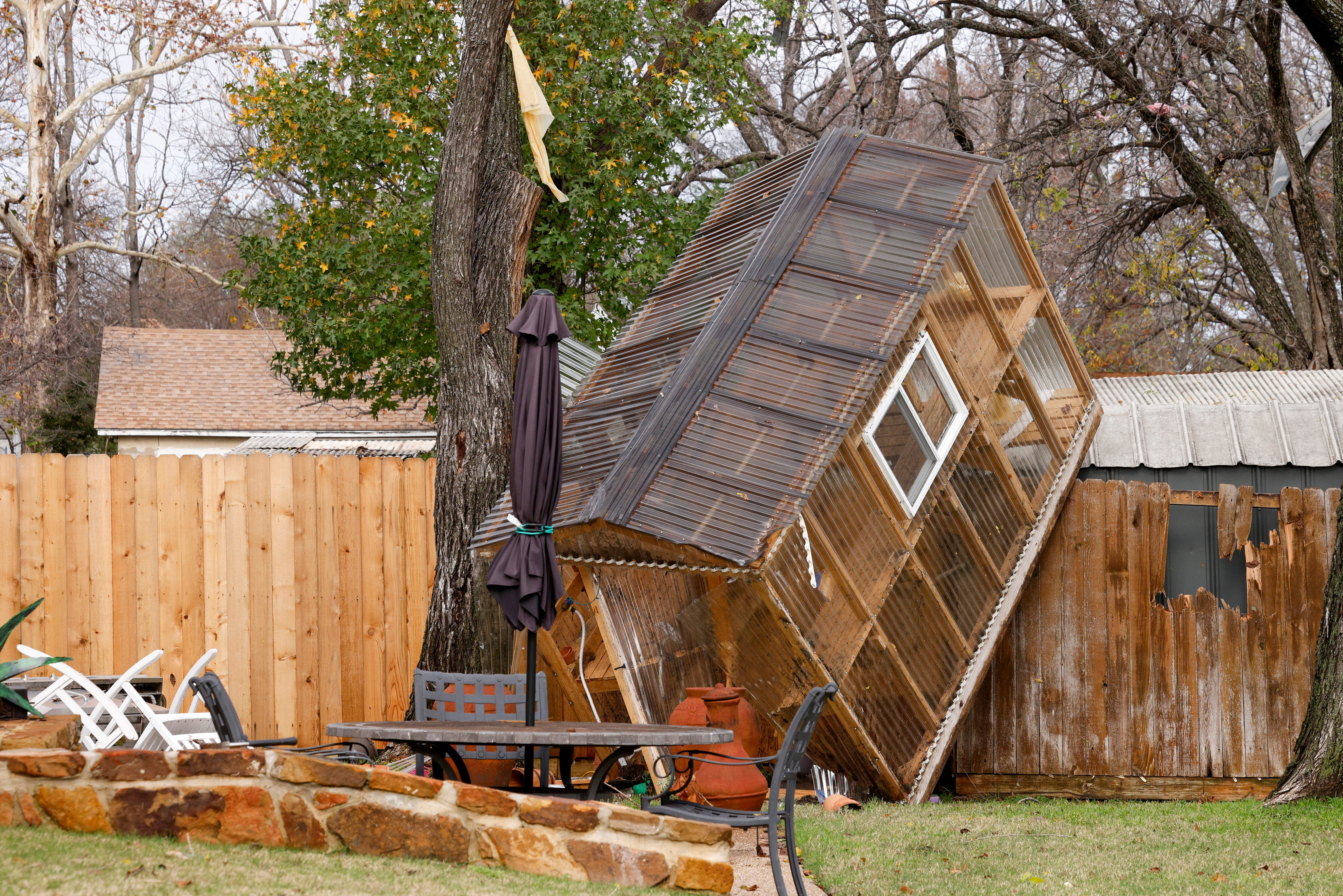 A greenhouse sits on a fence in the backyard of Randy Popiel’s home after a possible tornado in Grapevine, Texas