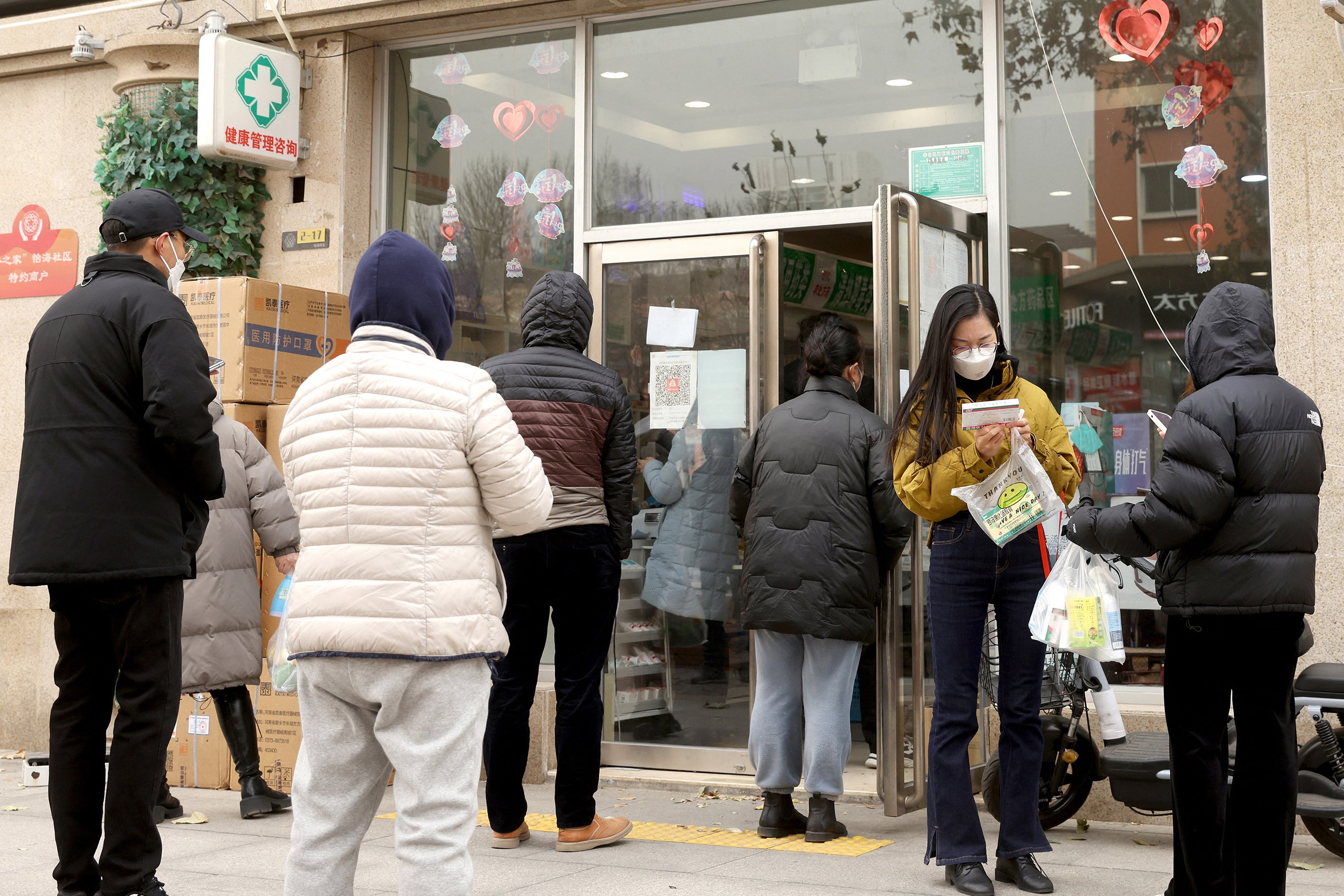 People queue to buy medicine at a drug store in Beijing on Monday