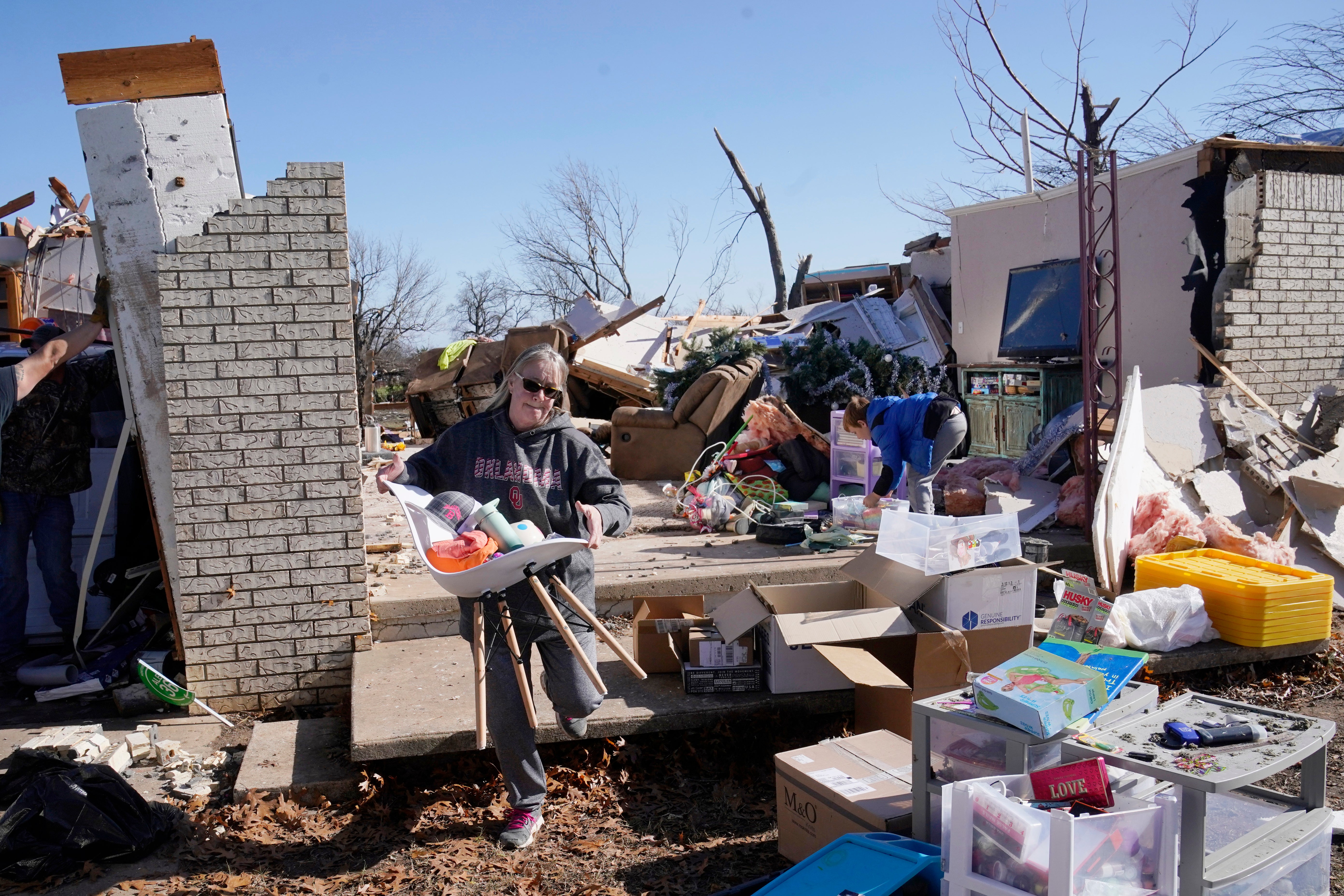 Belinda Penner carries belonging from her cousin’s home, destroyed by a tornado, Tuesday, Dec. 13, 2022, in Wayne, Oklahoma