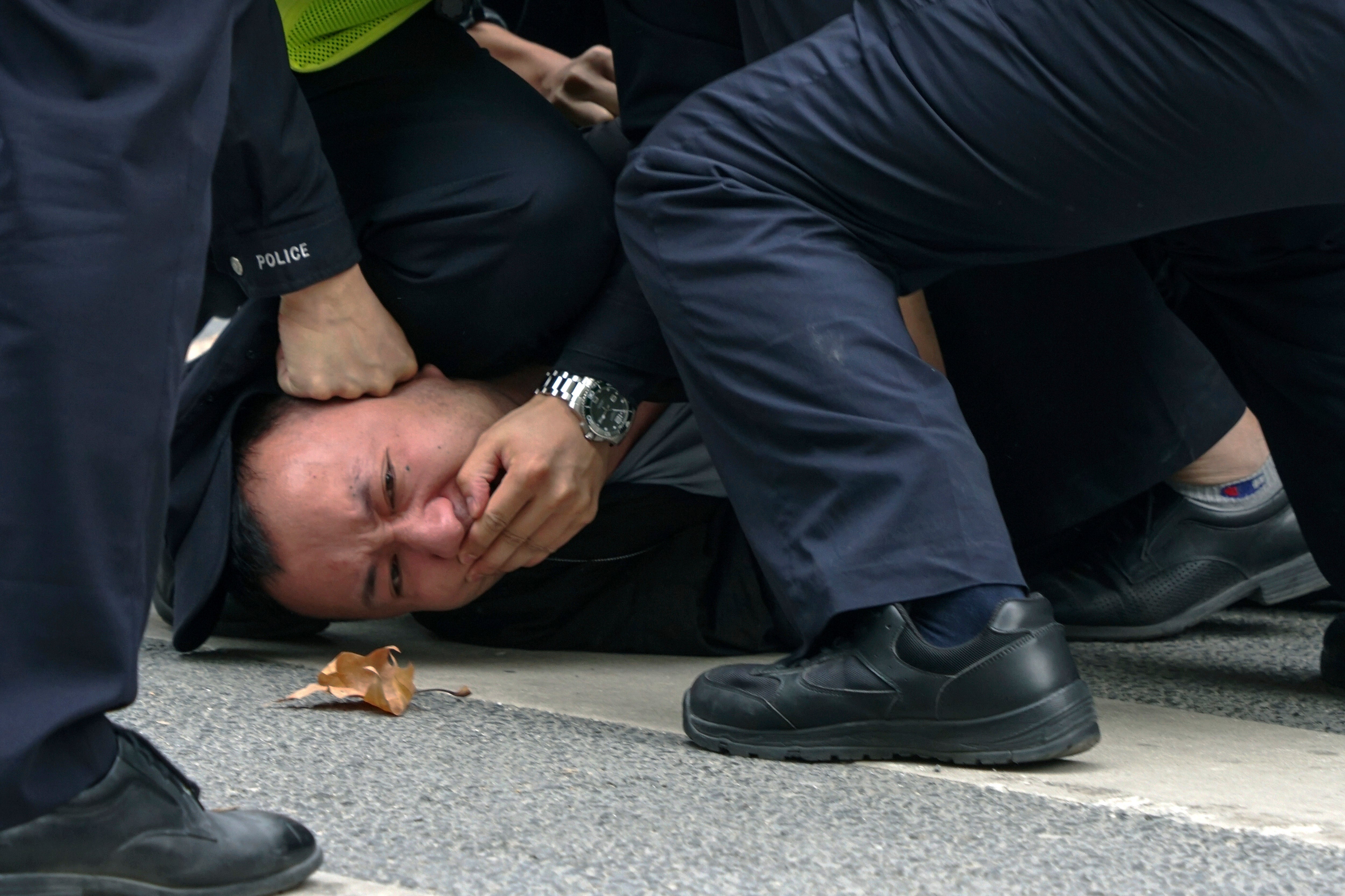 Policemen pin down and arrest a protester during a protest on a street in Shanghai, China