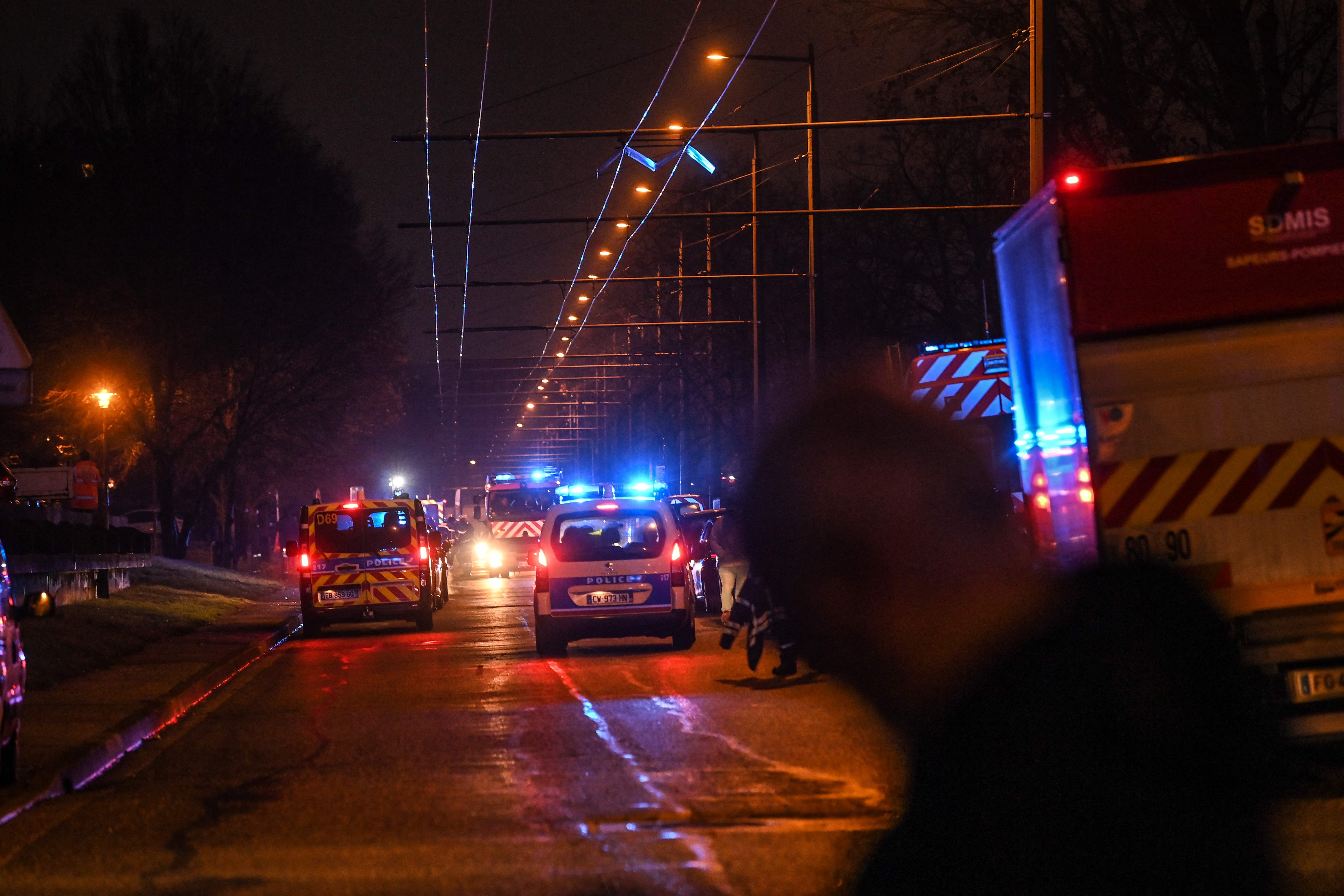 Policemen guard a security perimeter as firefighters and rescuers work in a building of the Mas-Du-Taureau quarter where a fire caused many victims, including children in Vaulx-en-Velin