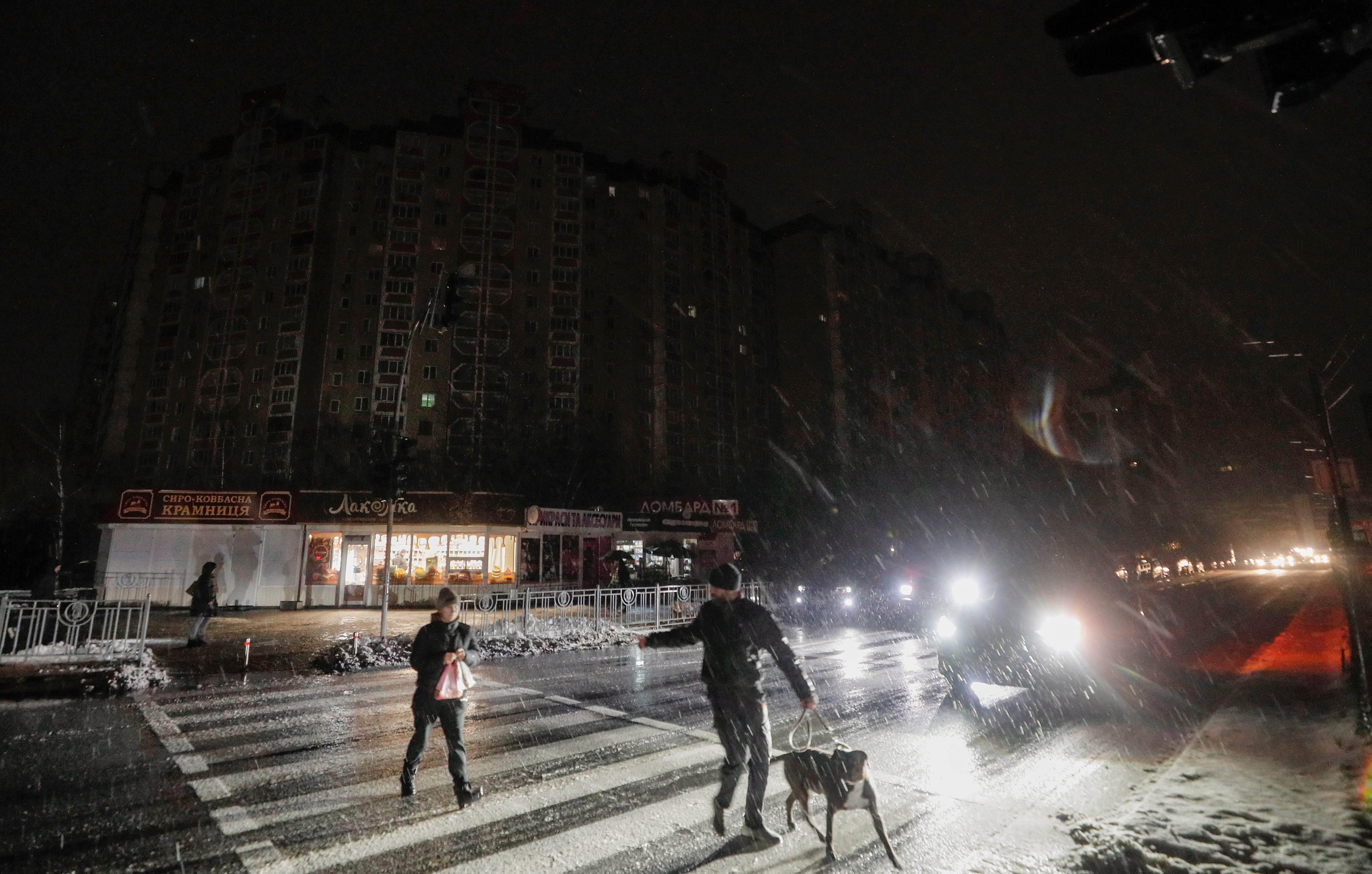 Residents cross a dark street as electricity is cut in Kyiv