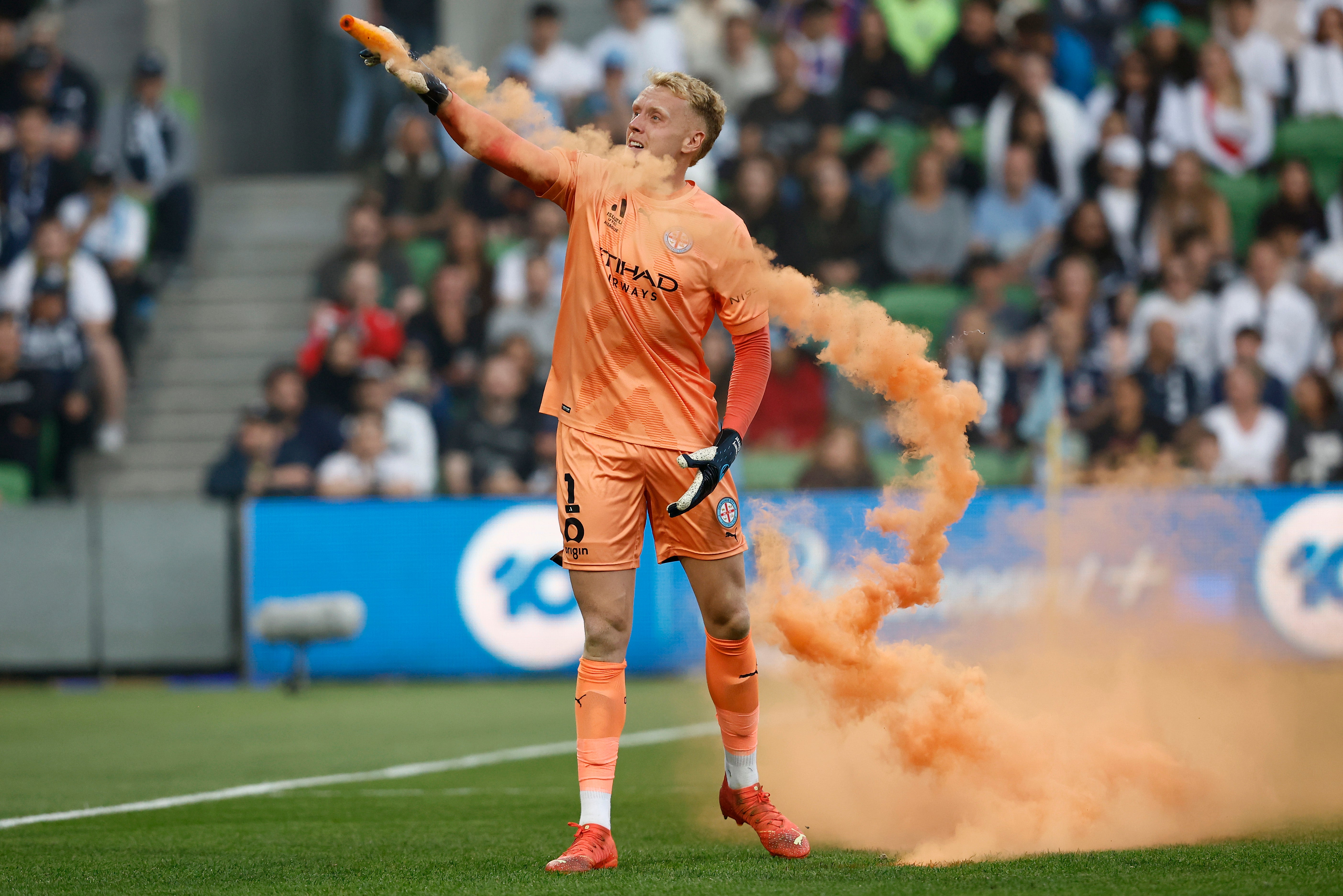 Tom Glover of Melbourne City picks up a flare to remove it from the pitch