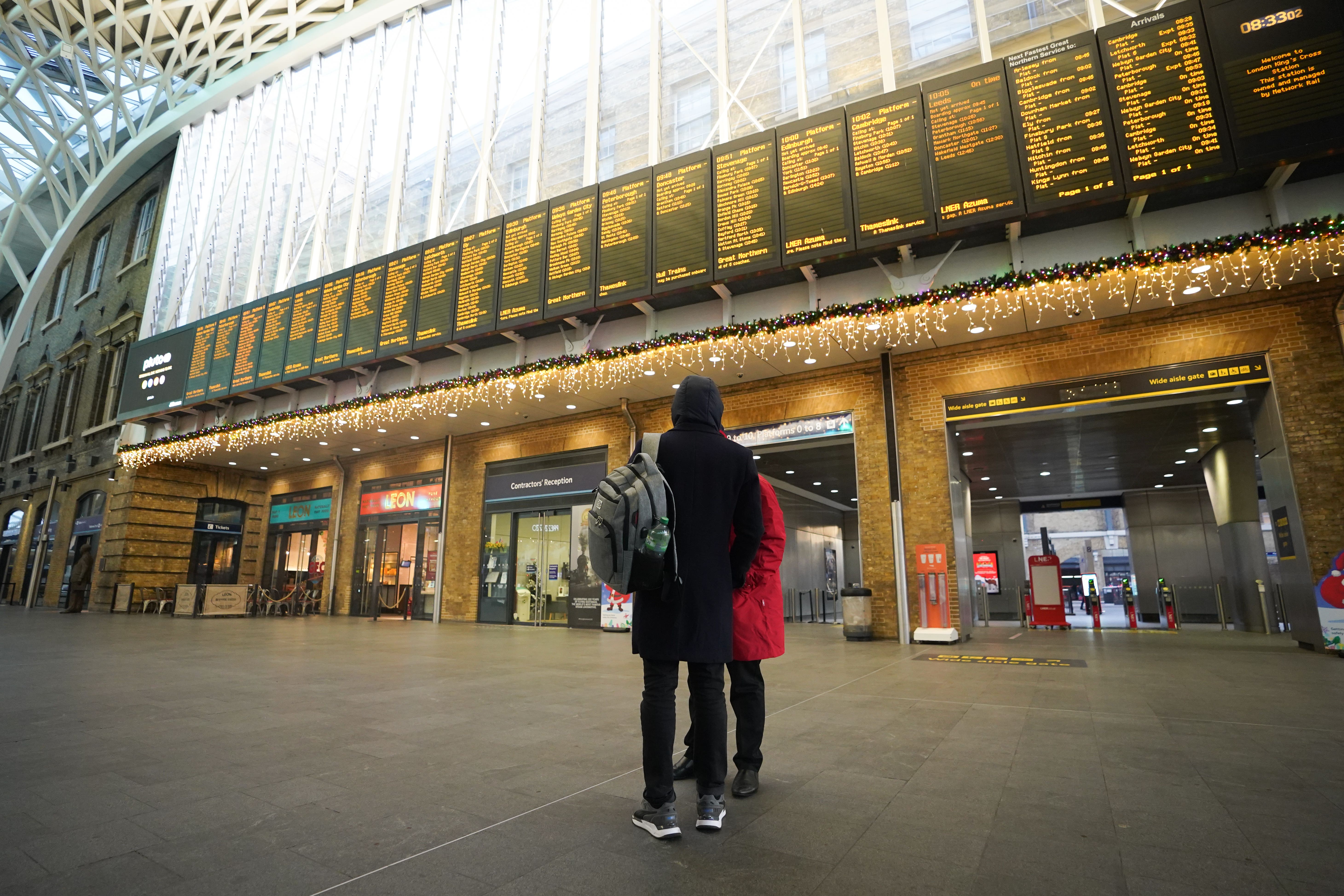 Passengers view departure boards at King’s Cross station in London (James Manning/PA)