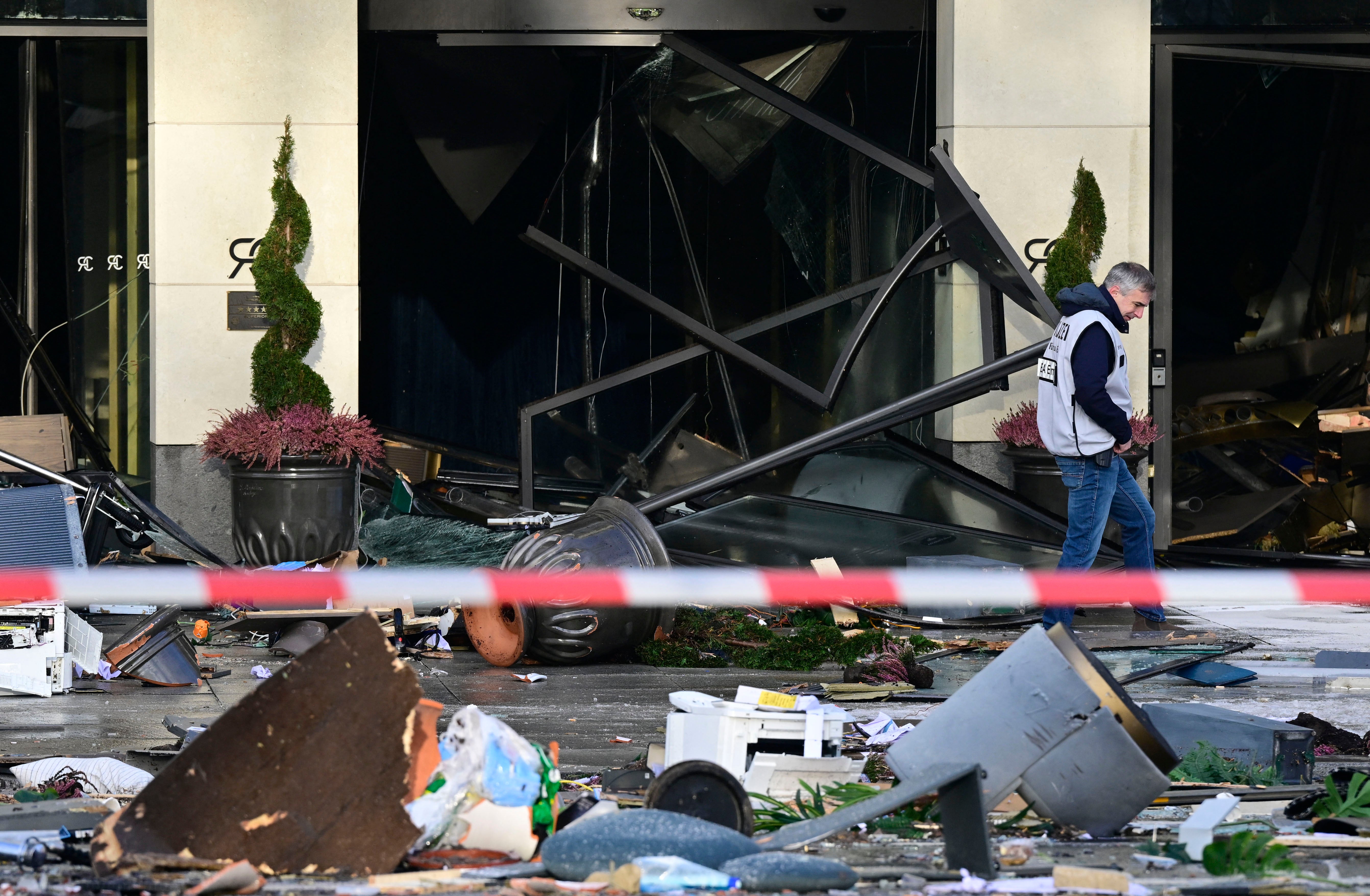 An investigator walks past debris covering the street in front of the Radisson Blu