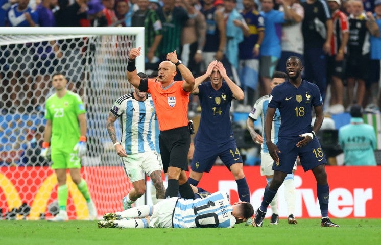 Adrien Rabiot reacts as referee Szymon Marciniak signals whilst Messi holds his head on the floor