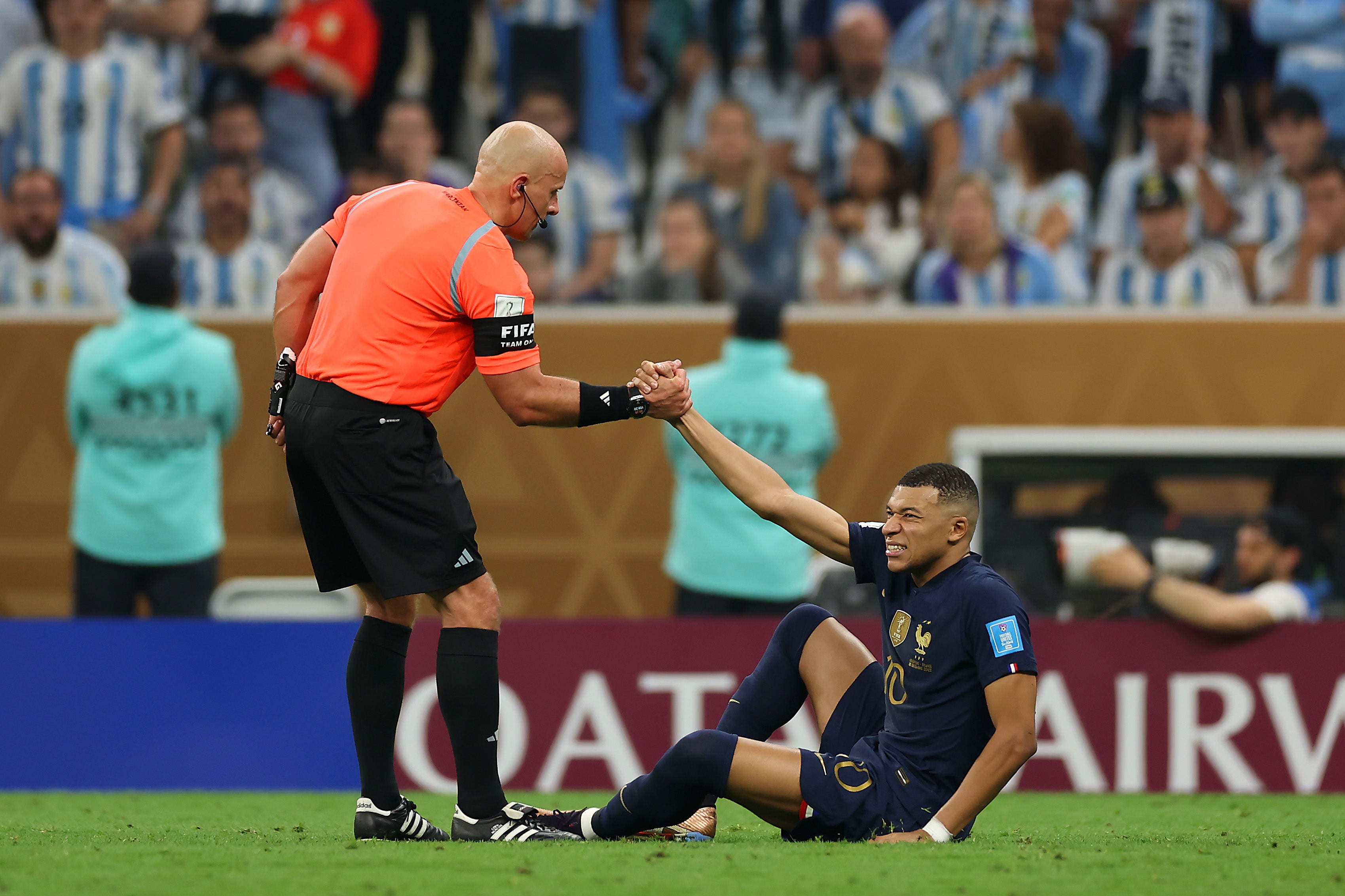 Szymon Marciniak helps up Kylian Mbappe