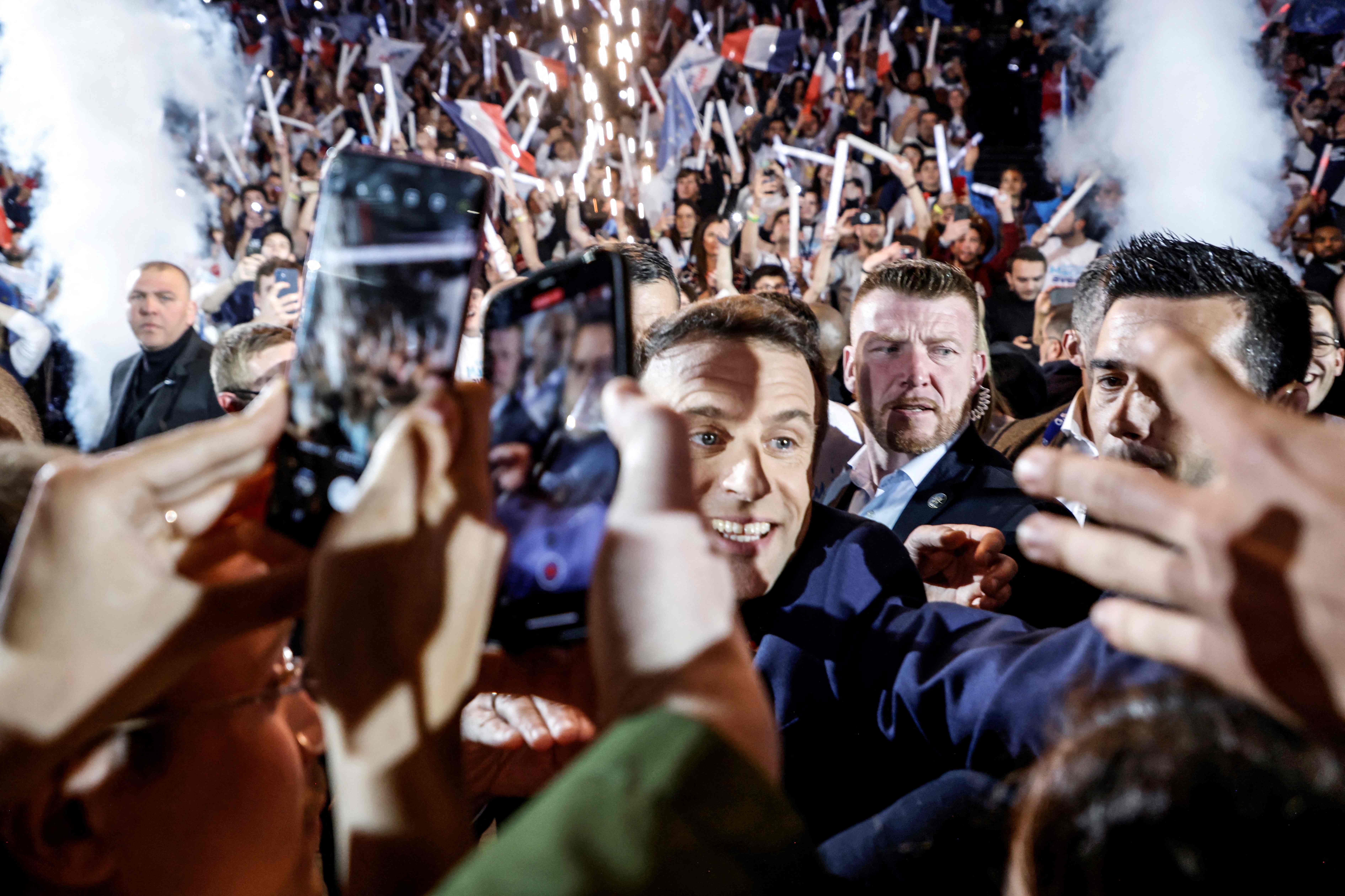 French President Emmanuel Macron greets people as he arrives for his first campaign meeting on the outskirts of Paris