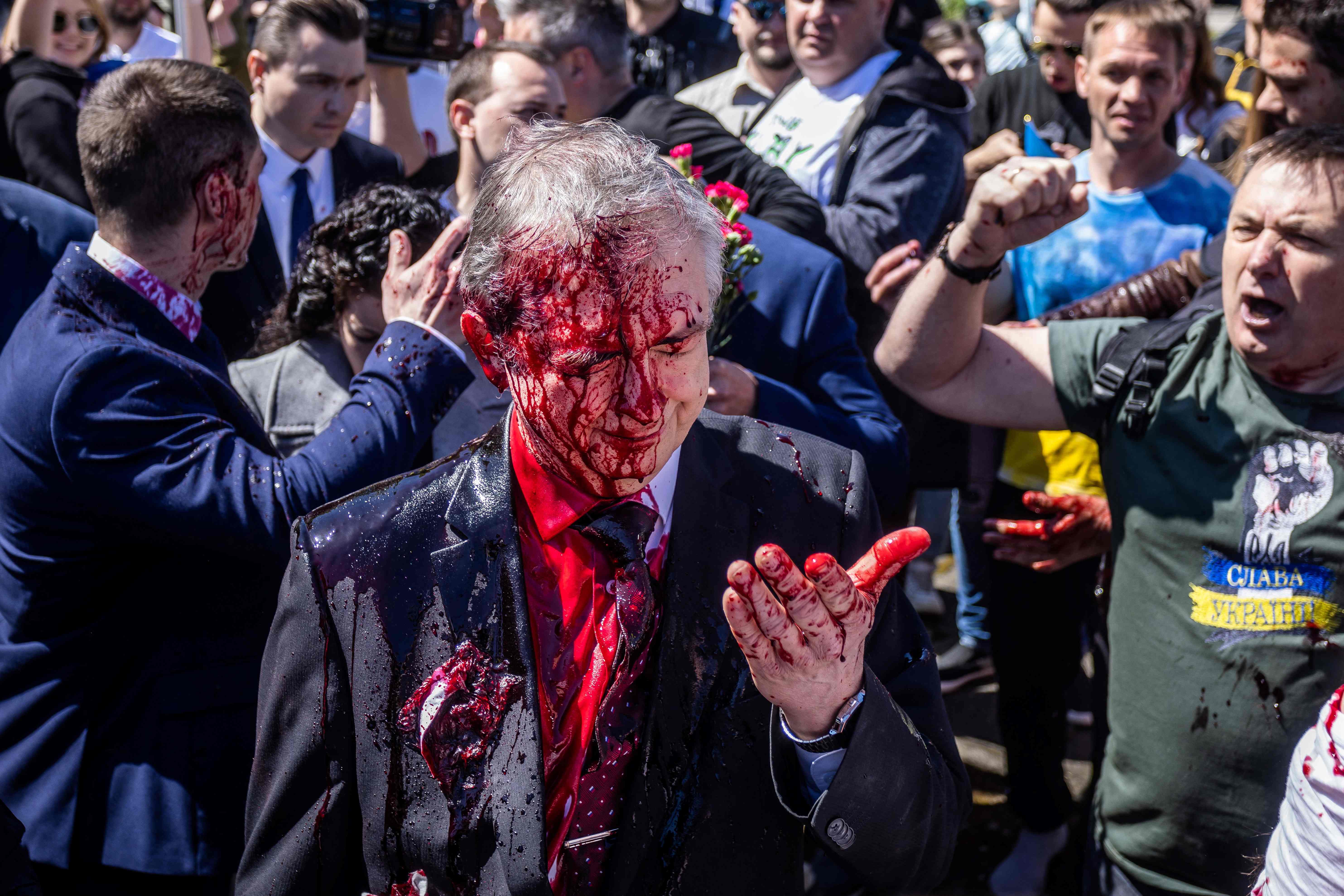 Russian Ambassador to Poland, Sergey Andreev reacts after being covered with red paint prior to a ceremony at the Soviet soldier war mausoleum in Warsaw