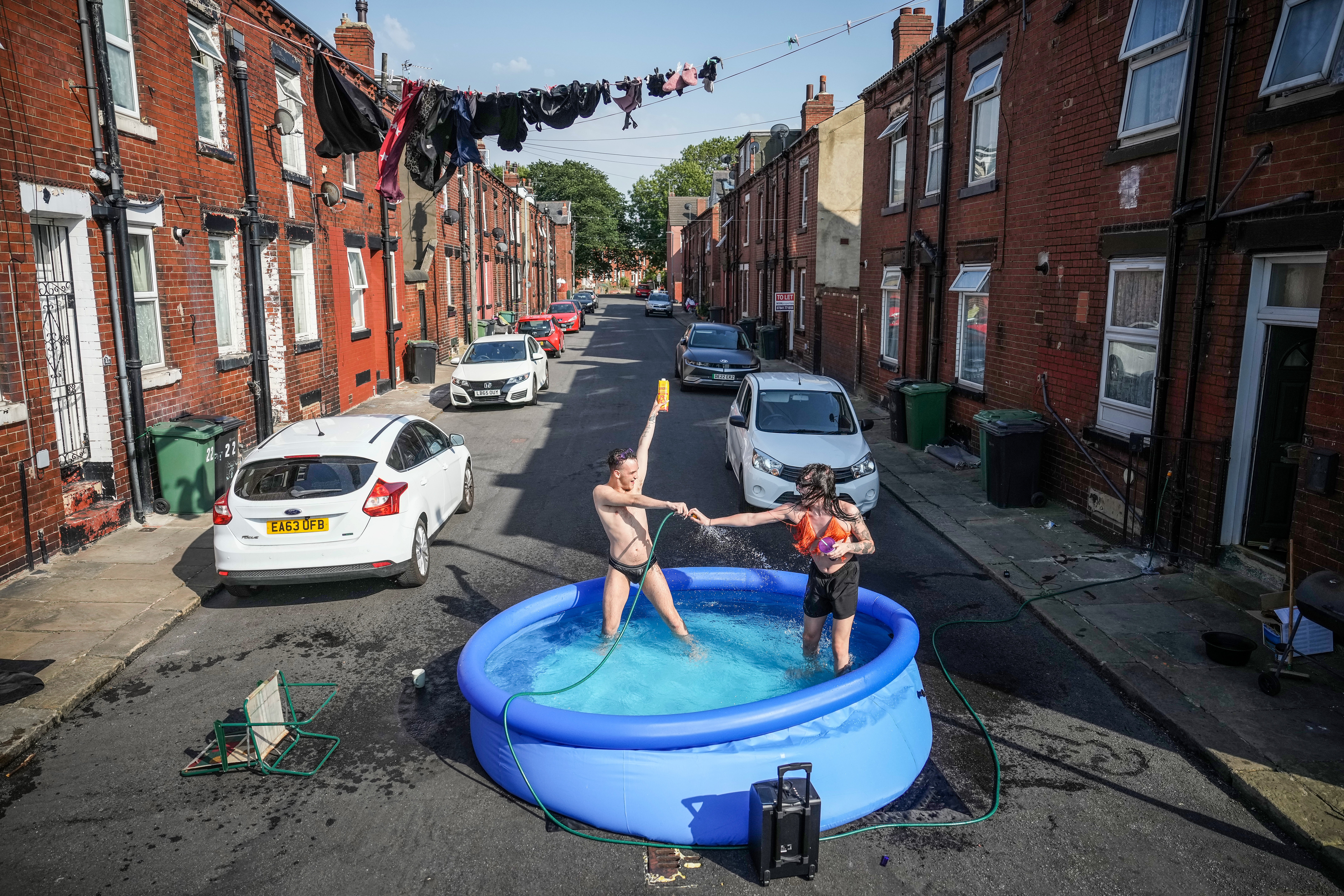 Residents take a dip in a paddling pool to cool off outside their home in Leeds during a heatwave across the UK