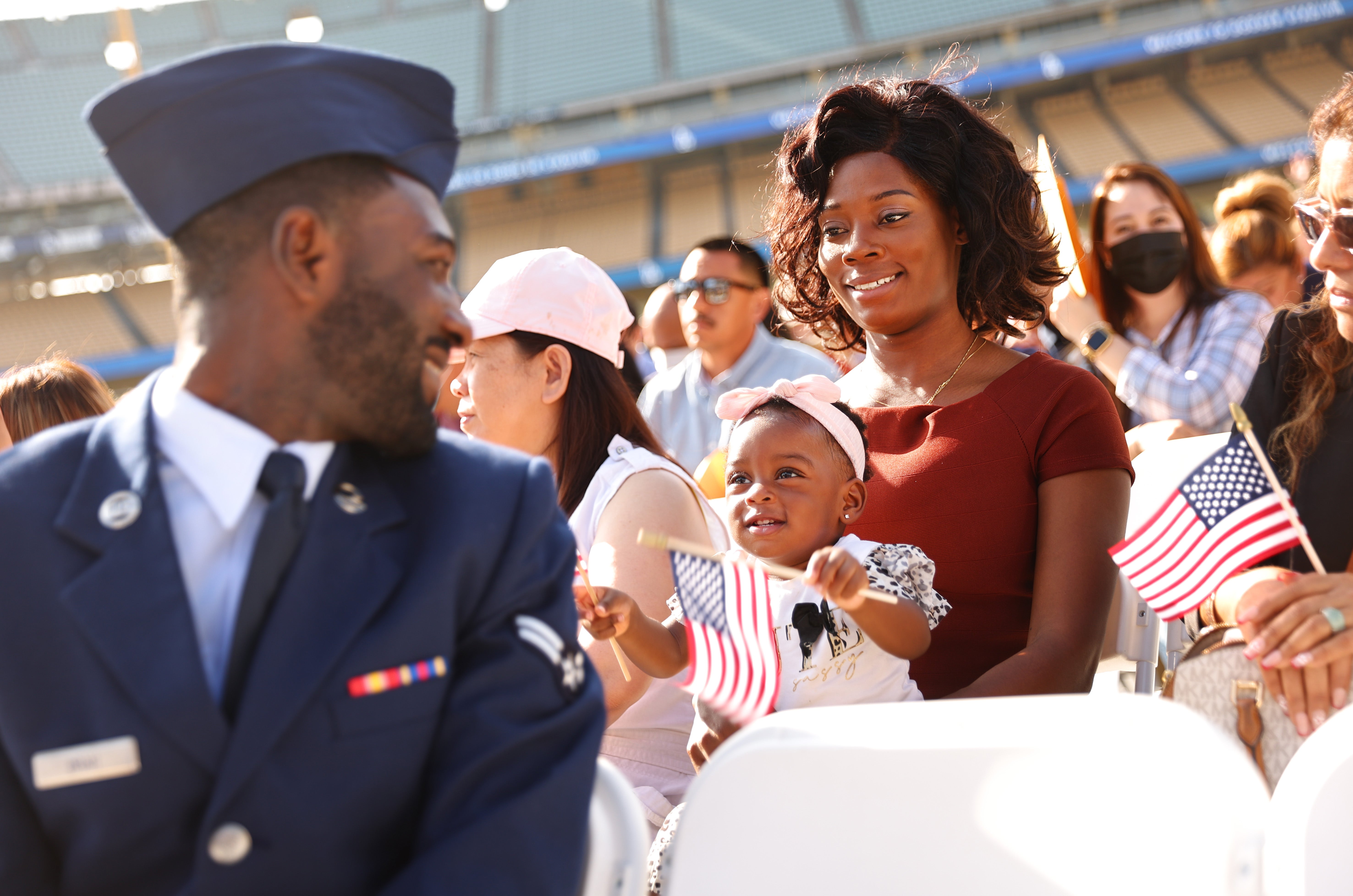 US Air Force Airman Michael Drah originally from Ghana, smiles with his wife and daughter before he becomes a US citizen at a naturalization ceremony at Dodger Stadium in Los Angeles, California