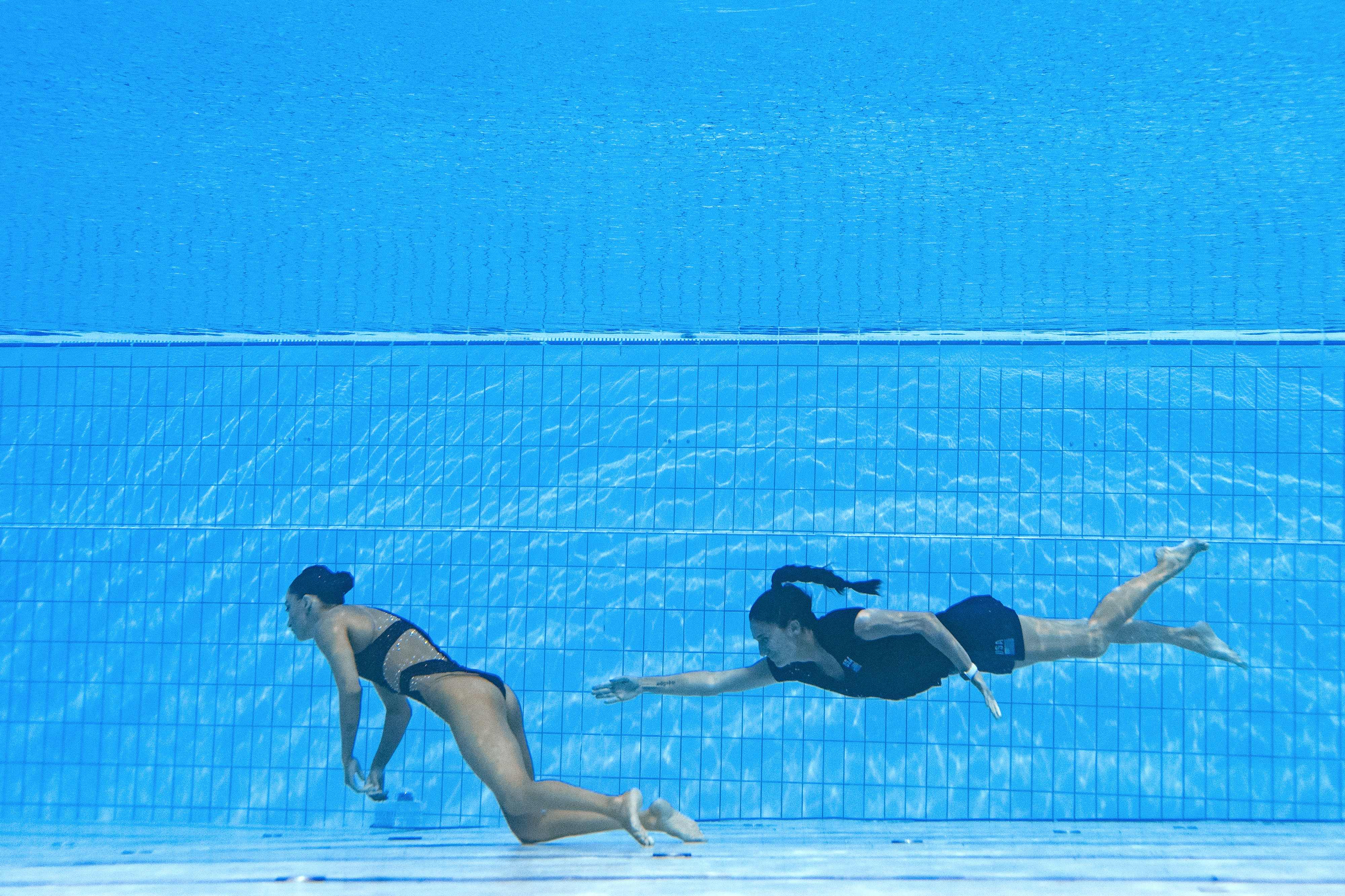 USA coach Andrea Fuentes, right, swims to recover Anita Alvarez, from the bottom of the pool after the athlete fainted whilst performing in the women’s solo free artistic swimming finals, at the Budapest World Aquatics Championships